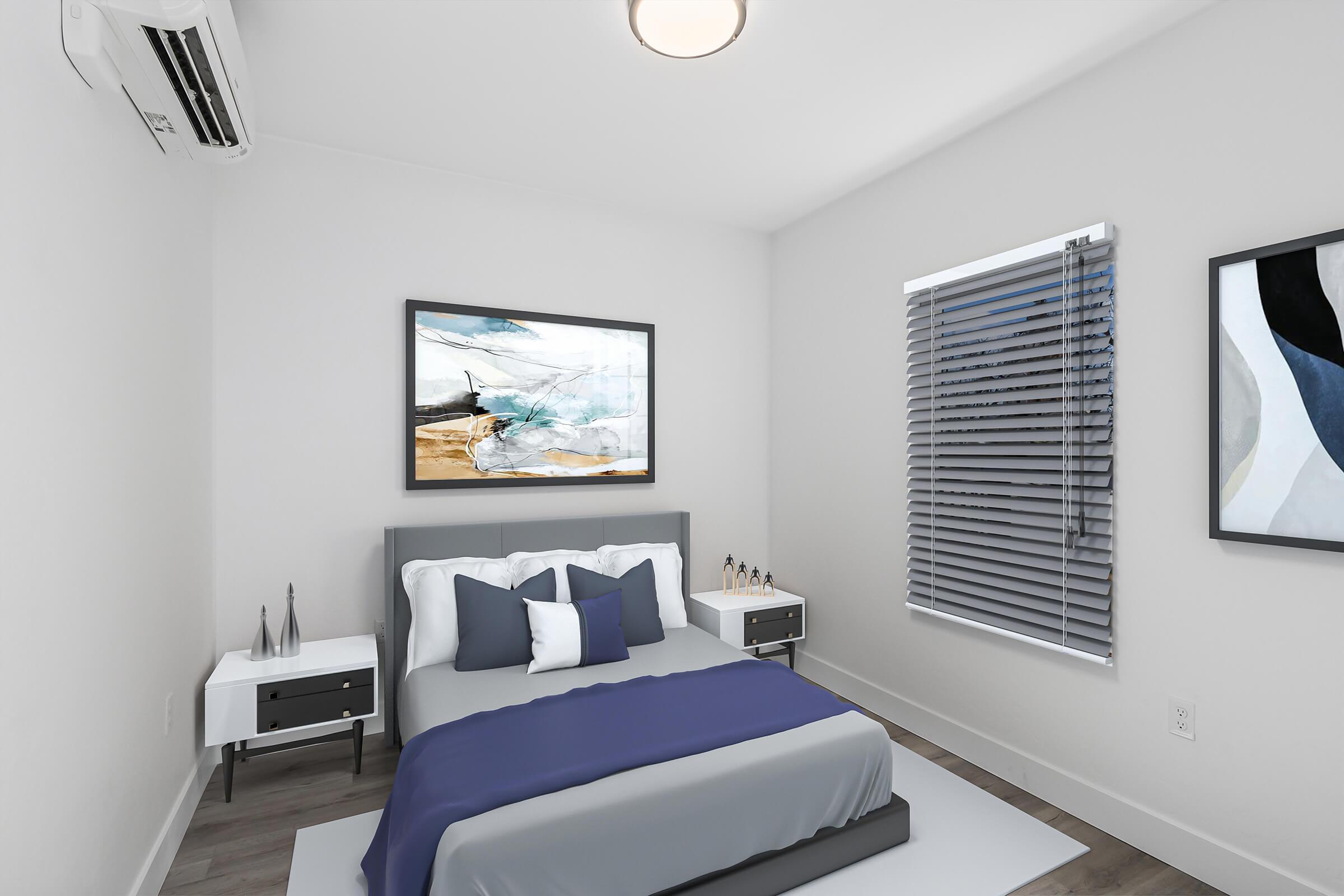 A modern bedroom featuring a double bed with blue and white bedding, two nightstands on either side, and a large artwork on the wall. There are two abstract paintings, a window with blinds letting in natural light, and an air conditioning unit on the wall. The overall decor is minimalist and contemporary.