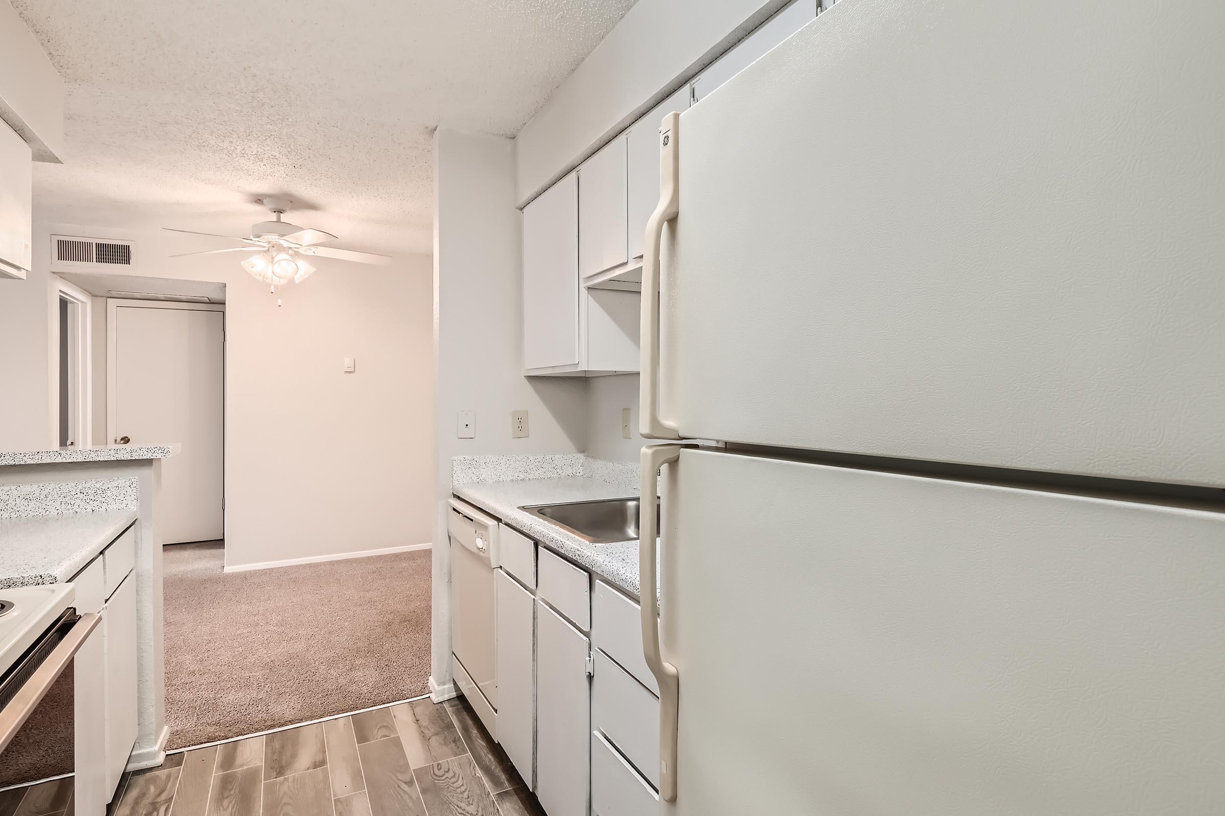 An apartment kitchen at Rise North Arlington with white cabinets near the carpeted dining area.