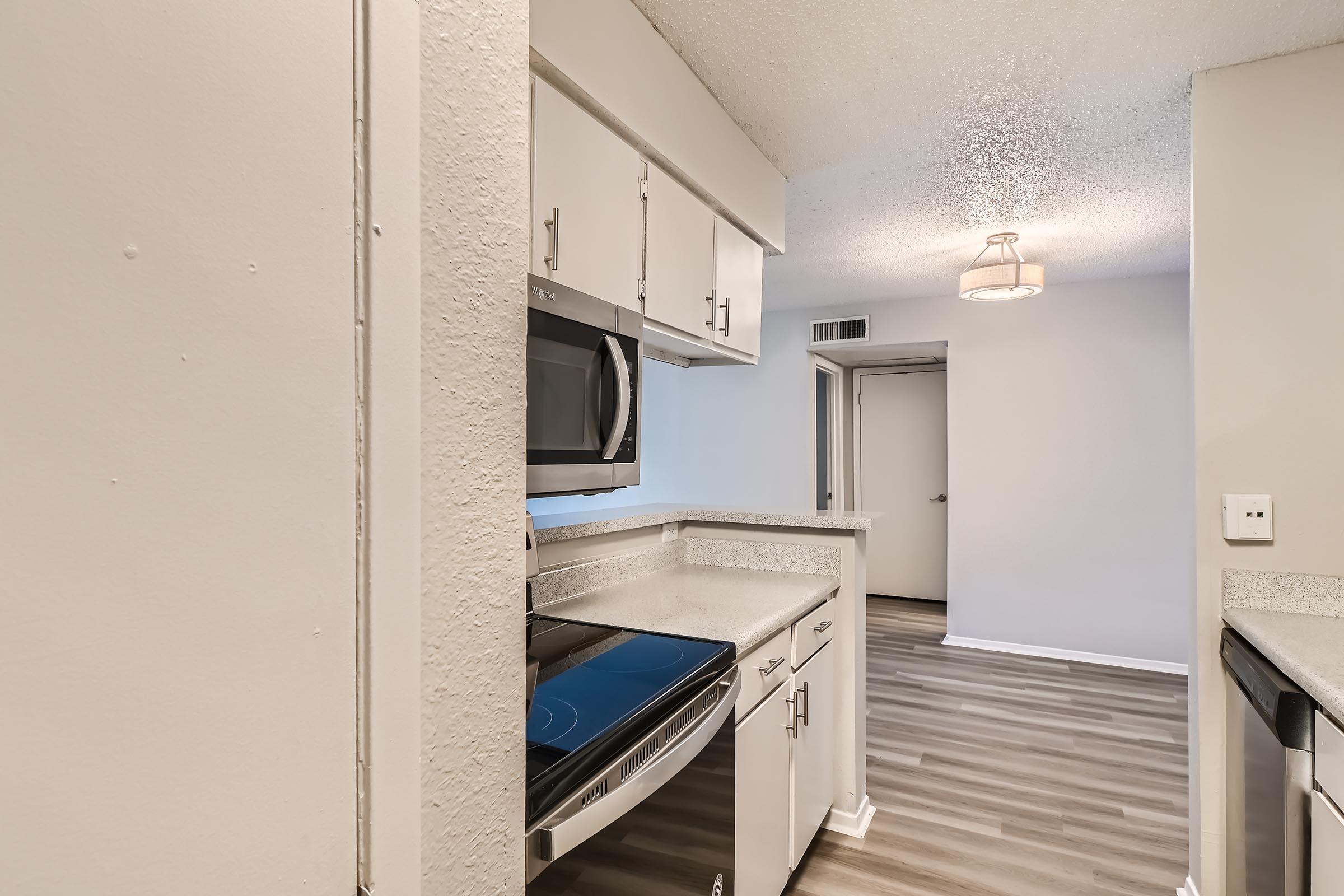 An apartment kitchen with white cabinets and stainless steel appliances at Rise North Arlington.