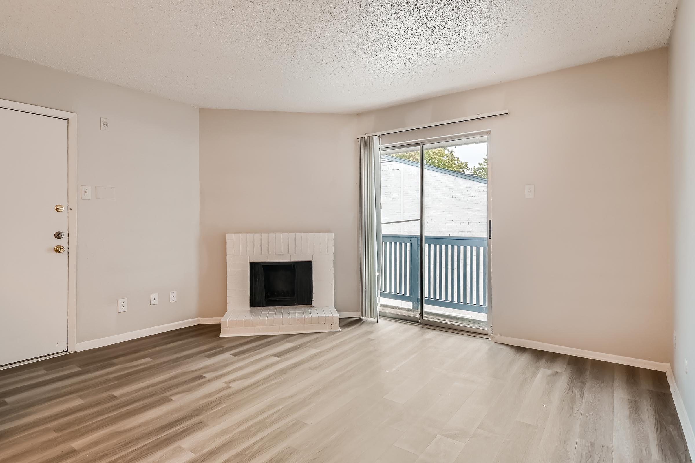 An apartment living room with wood-style floors, a fireplace, and glass sliding doors leading to the balcony at Rise North Arlington.