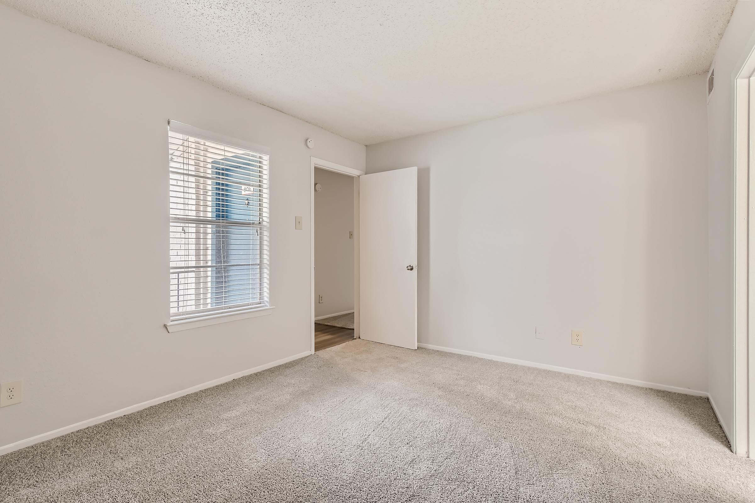 A carpeted bedroom with a large window at Rise North Arlington apartments.
