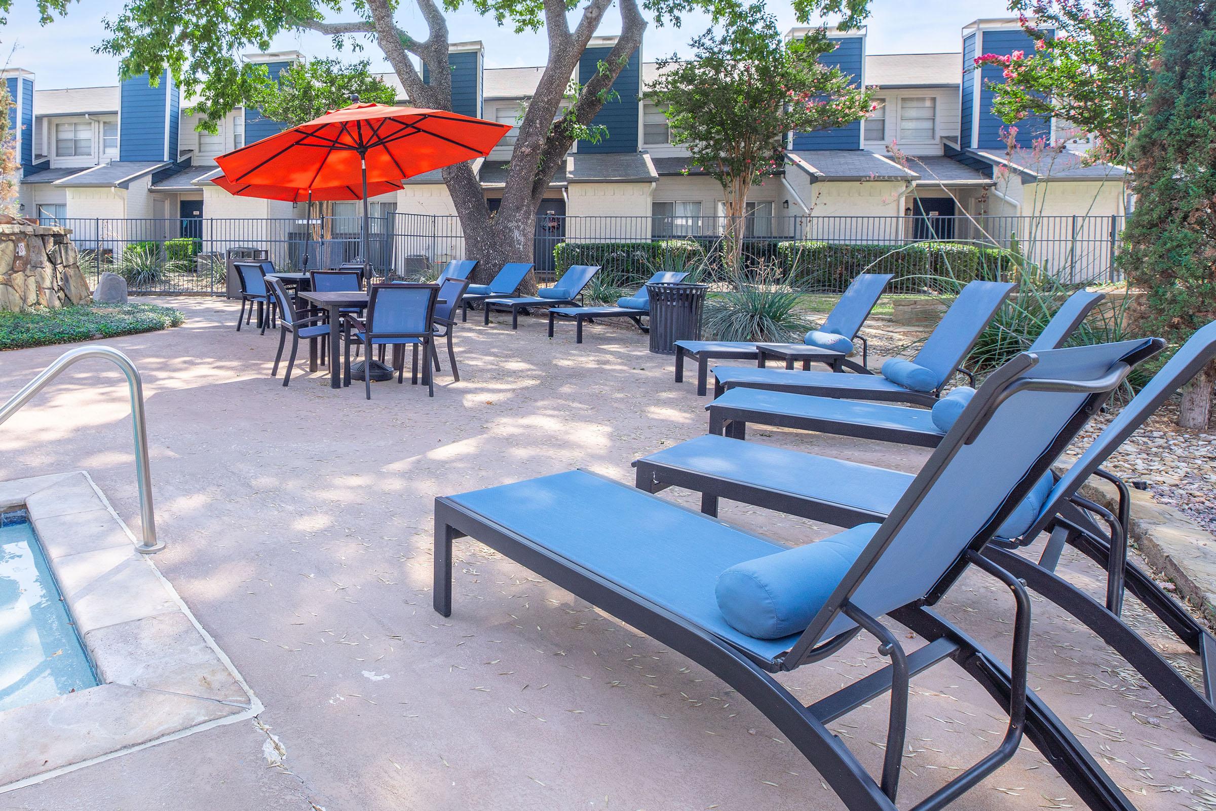 Many loungers and tables in the pool area at Rise North Arlington.