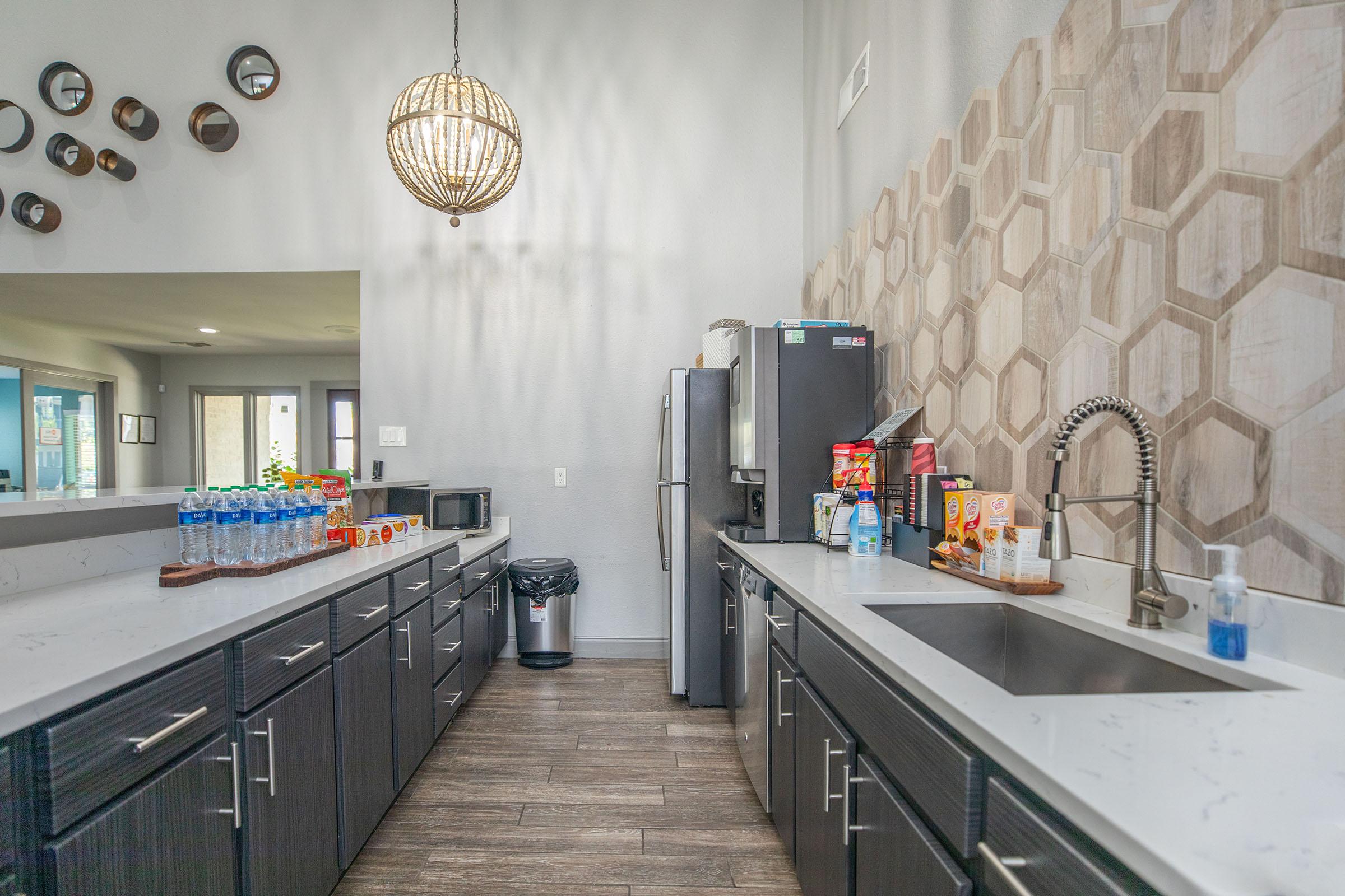 The expansive clubhouses kitchen with a bar counter and stainless steel appliances at Rise North Arlington.