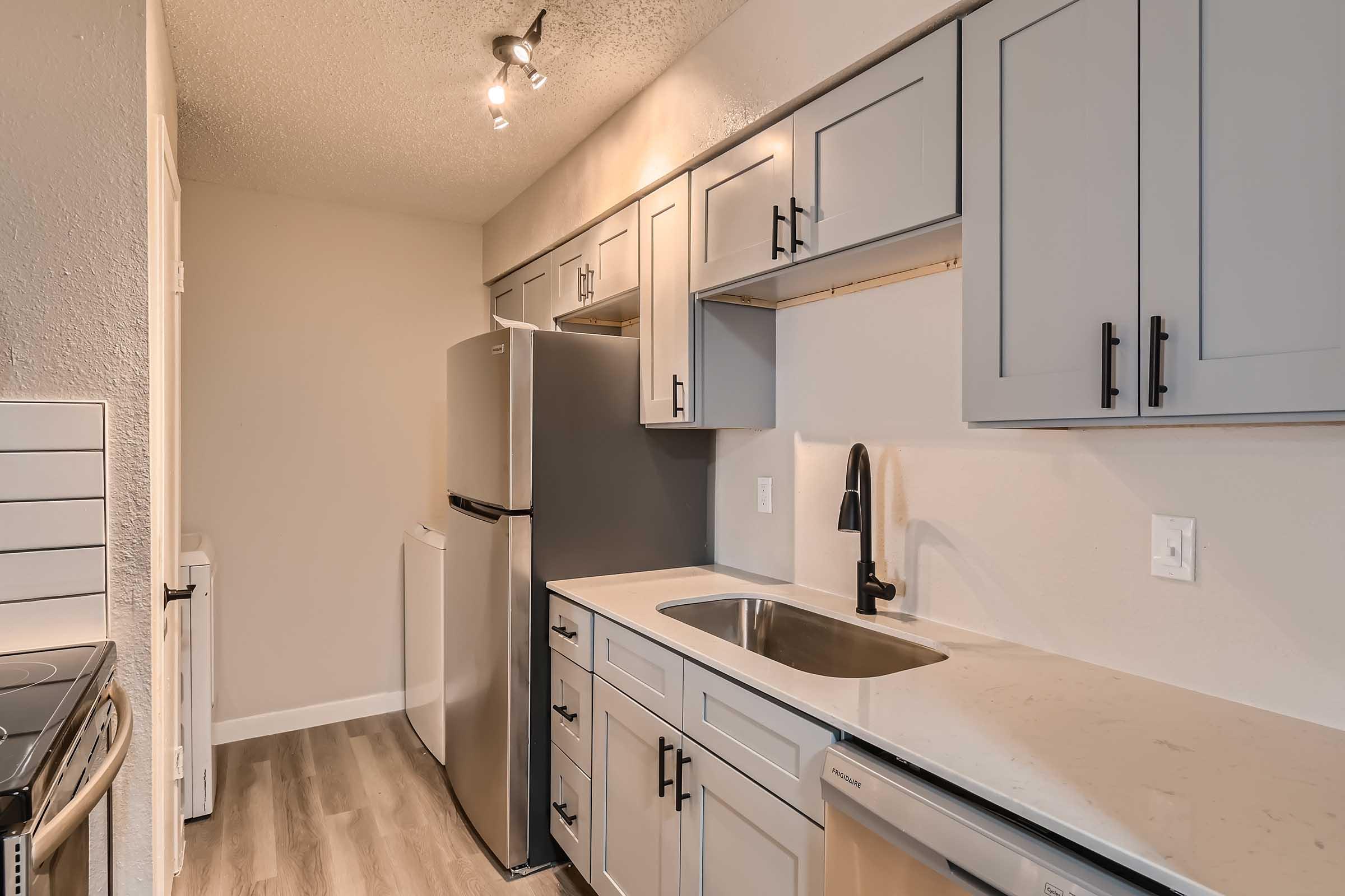 An apartment kitchen with stainless steel appliances, a washer and dryer, and shaker cabinets at Rise North Arlington.