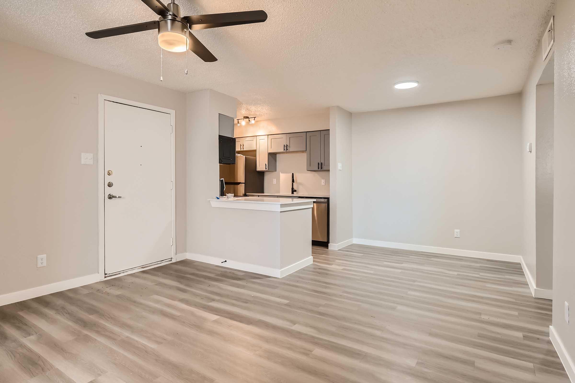 Rise North Arlington open-concept living room with a ceiling fan, wood-style flooring and a kitchen.