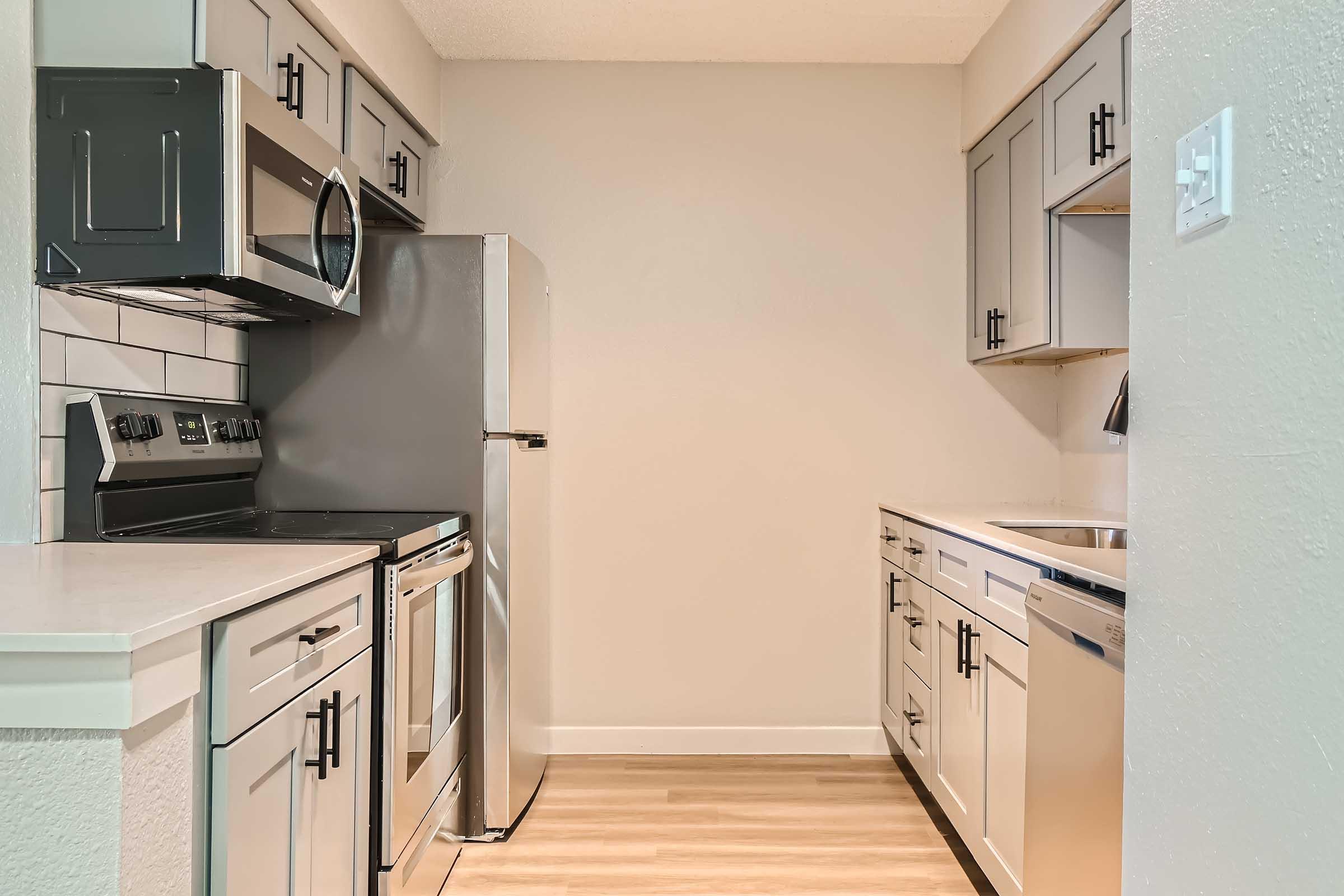 The apartment kitchen at with grey shaker cabinets and stainless steel appliances at Rise North Arlington.