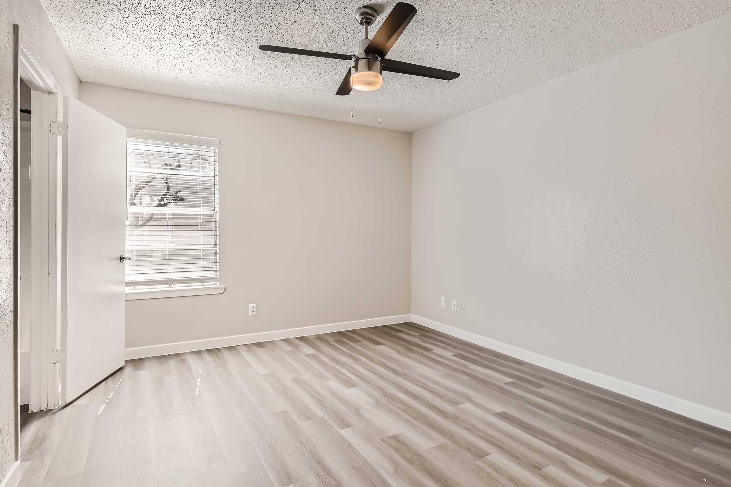 A bedroom with wood-style flooring and a window at Rise North Arlington.