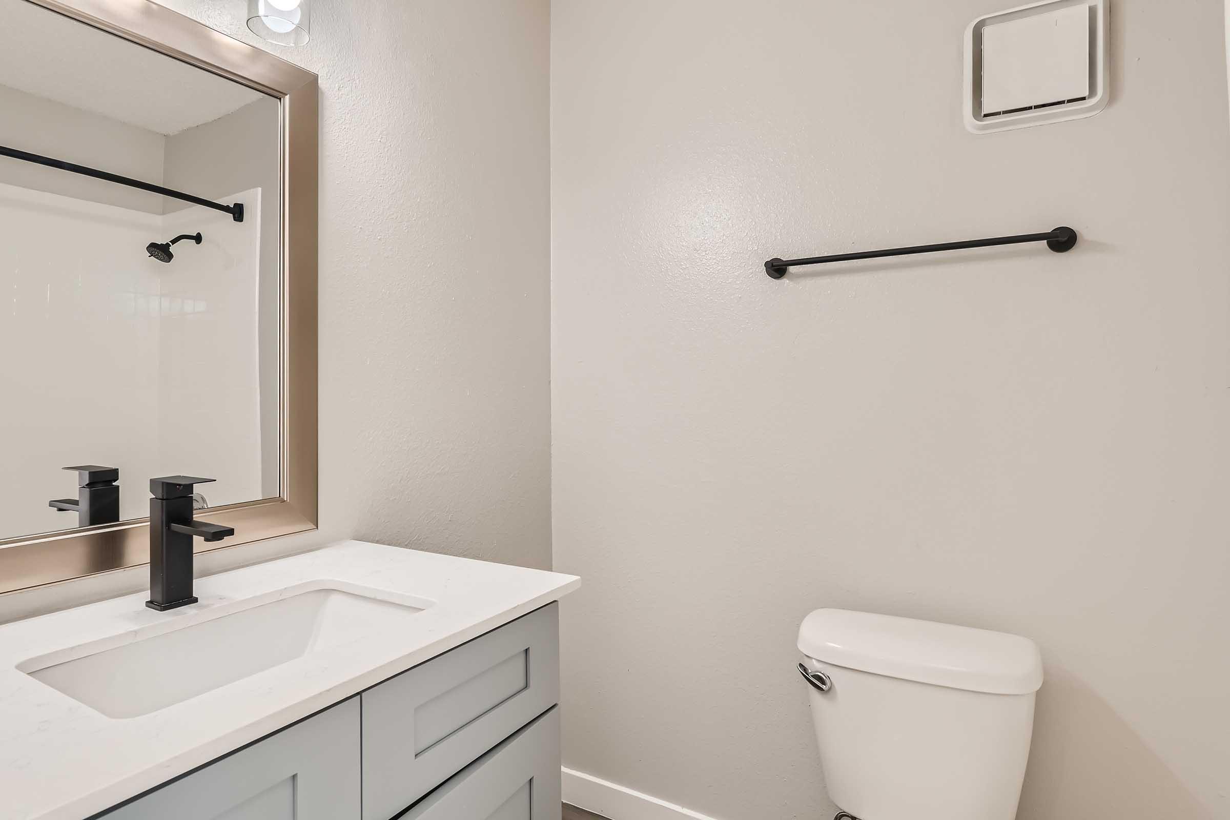 An apartment bathroom with a quartz vanity and a mirror at Rise North Arlington.