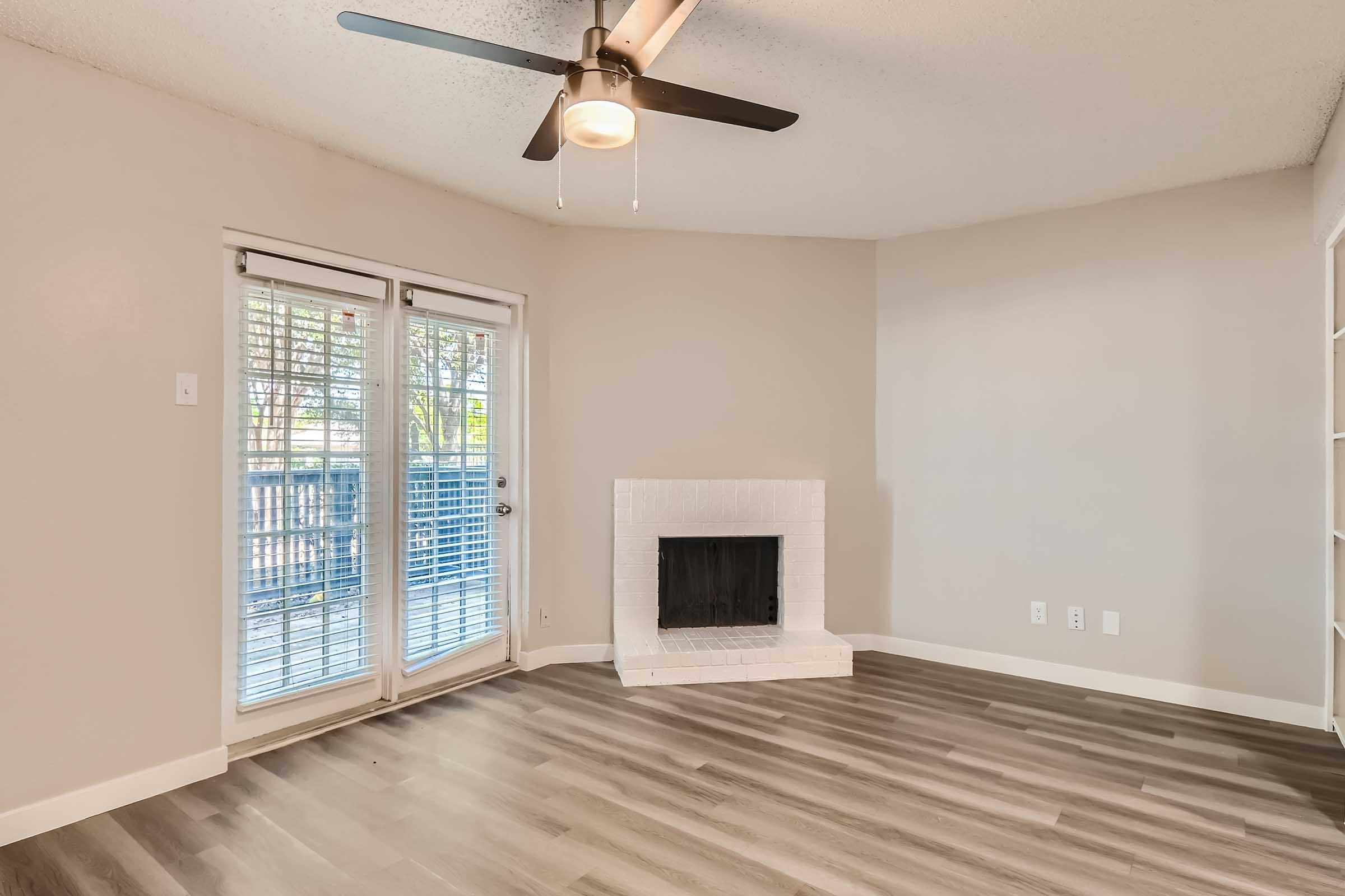 A living room with wood-style floors and glass doors leading to the balcony at Rise North Arlington.