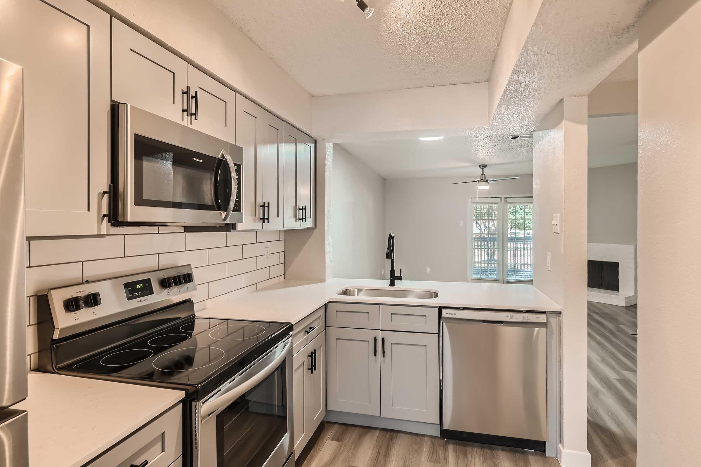 An apartment kitchen with grey shaker cabinets and stainless steel appliances at Rise North Arlington.