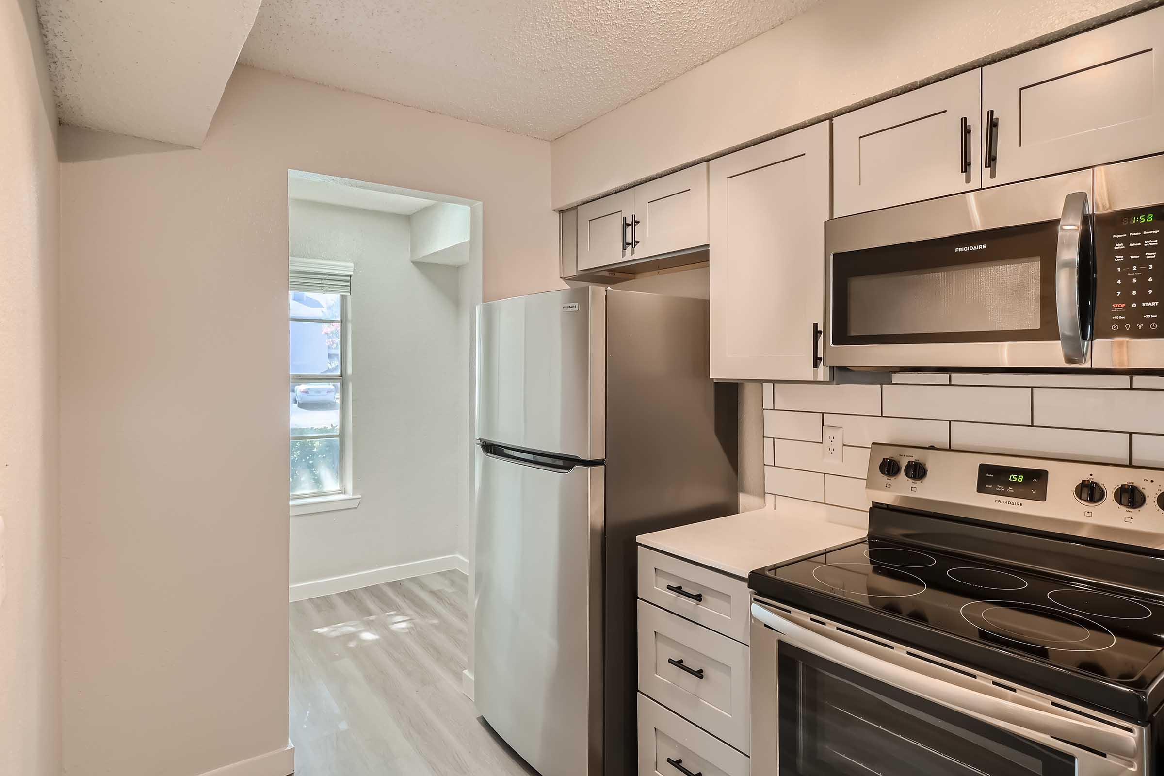 An apartment kitchen with stainless steel appliances and a view of the dining area at Rise North Arlington.
