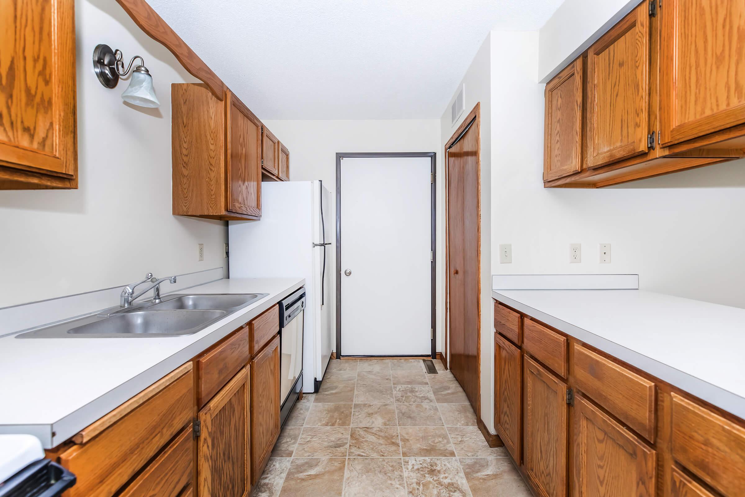 a kitchen with wooden cabinets and a bed