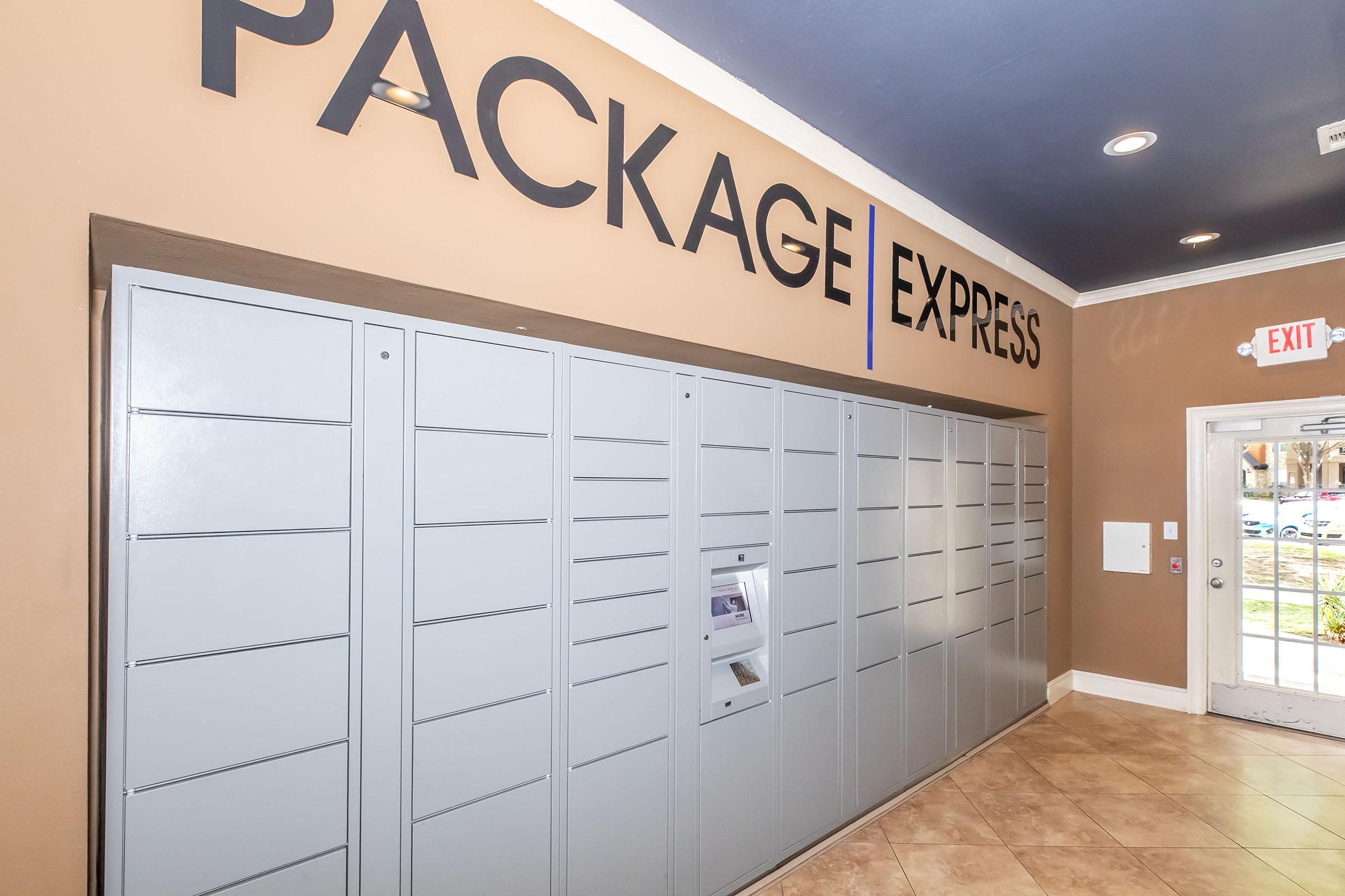 Interior view of a package delivery area featuring a gray package locker system against a brown wall. Above the lockers, the words "PACKAGE EXPRESS" are displayed prominently. The space includes an exit sign and has tiled flooring, creating a functional area for receiving packages.