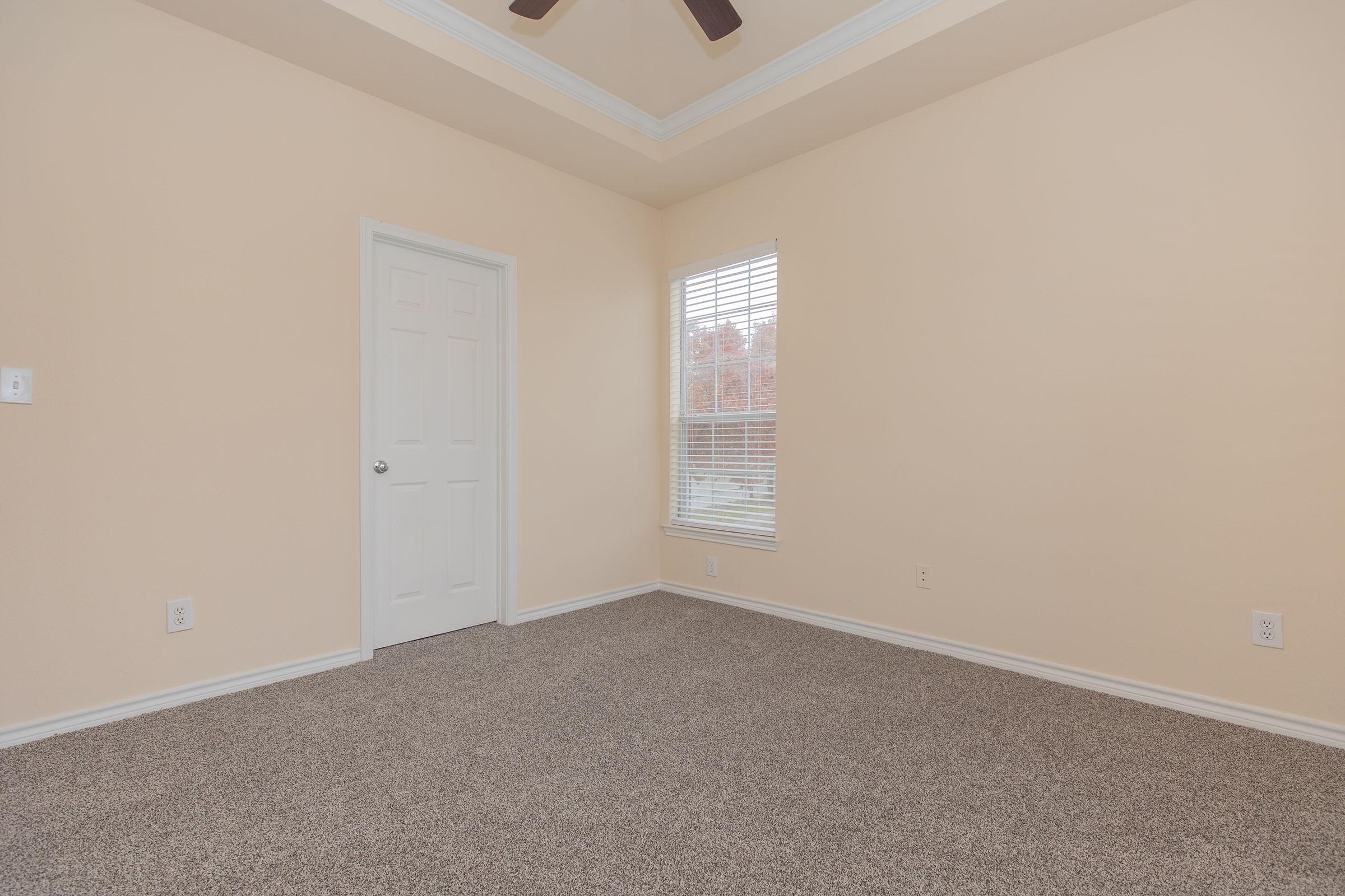 carpeted vacant bedroom with a closed bathroom door