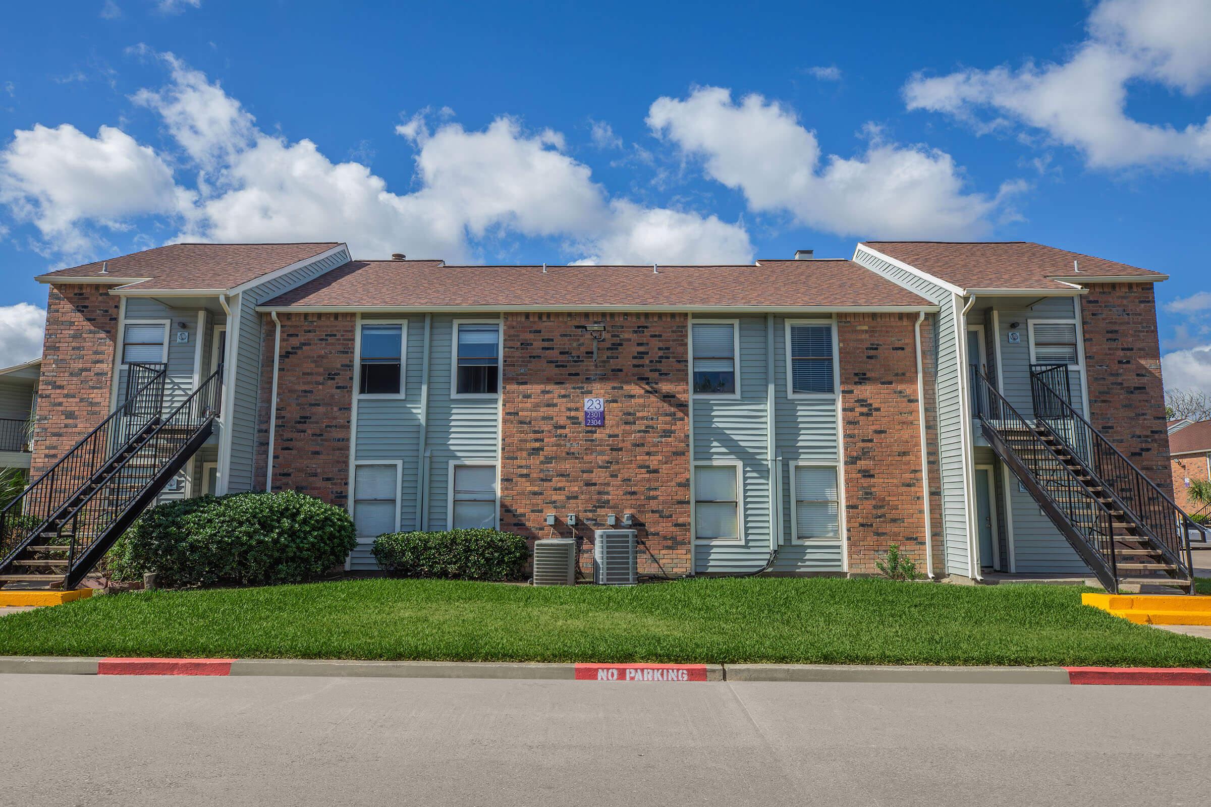 a large brick building with grass in front of a house