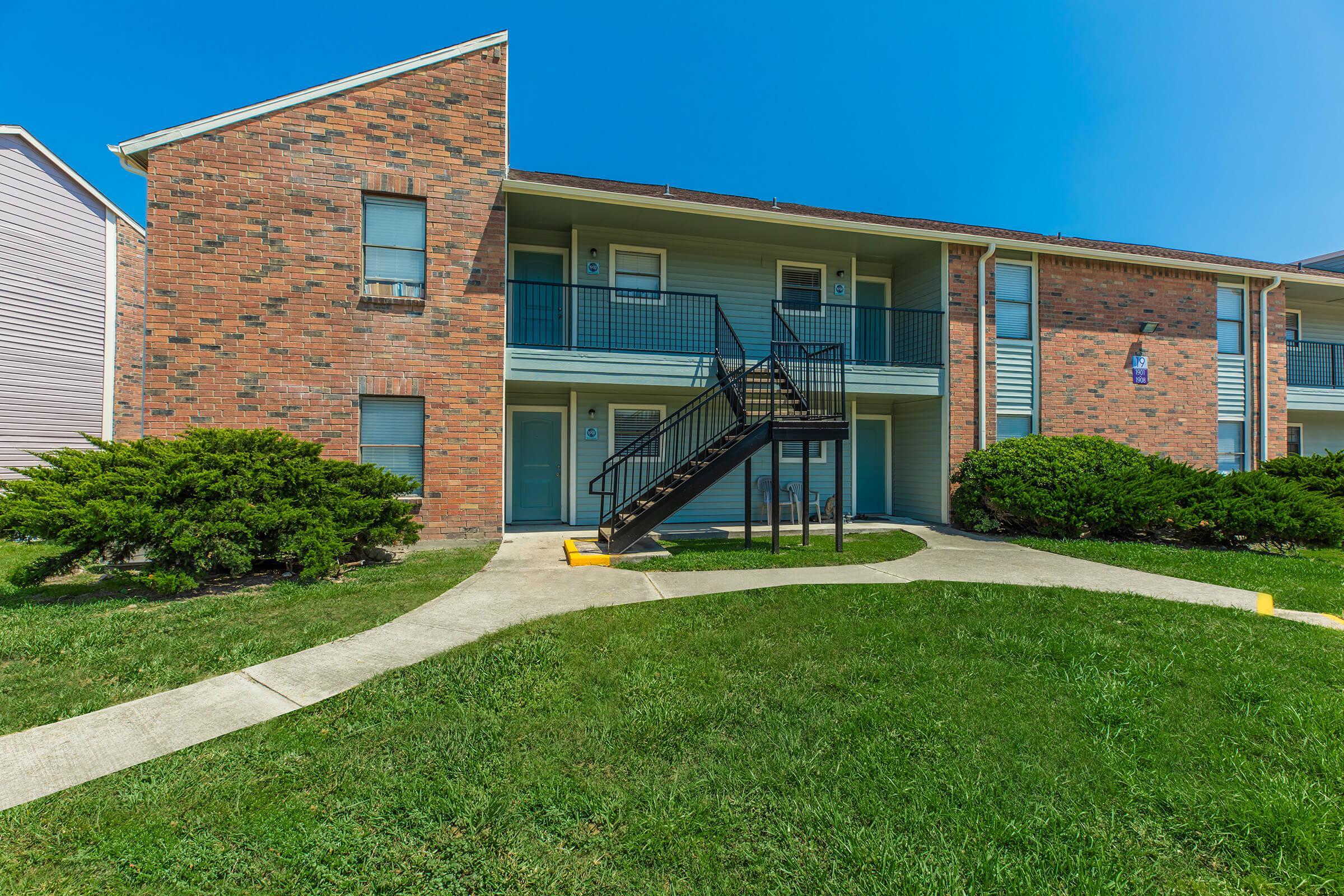 a house with a lawn in front of a brick building