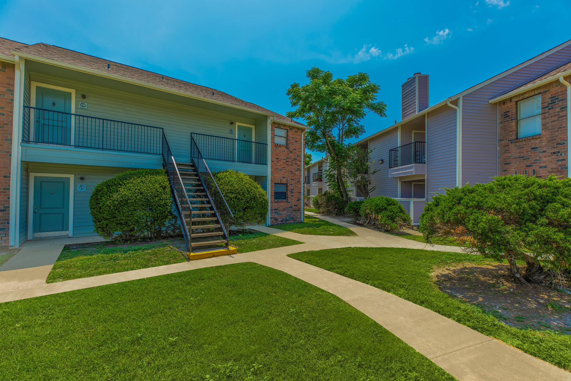 a house with a lawn in front of a brick building