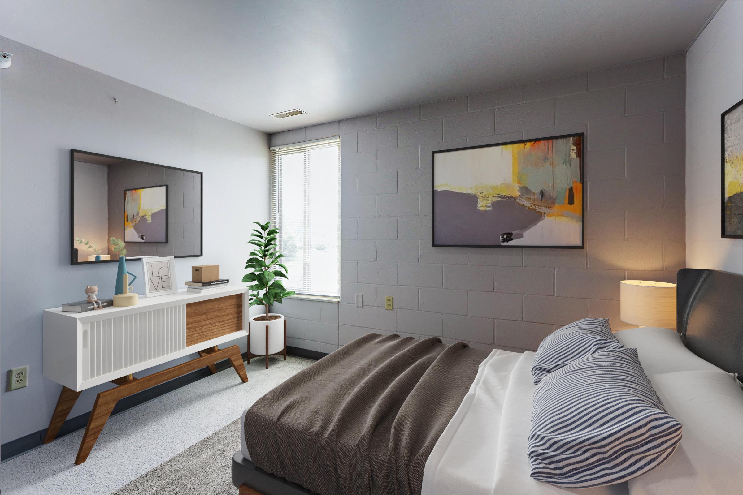 A modern bedroom featuring a king-sized bed with gray and white striped pillows, a stylish nightstand, and a wooden dresser. There is a large mirror above the dresser, two abstract paintings on the walls, a potted plant near the window, and soft natural light illuminating the room.