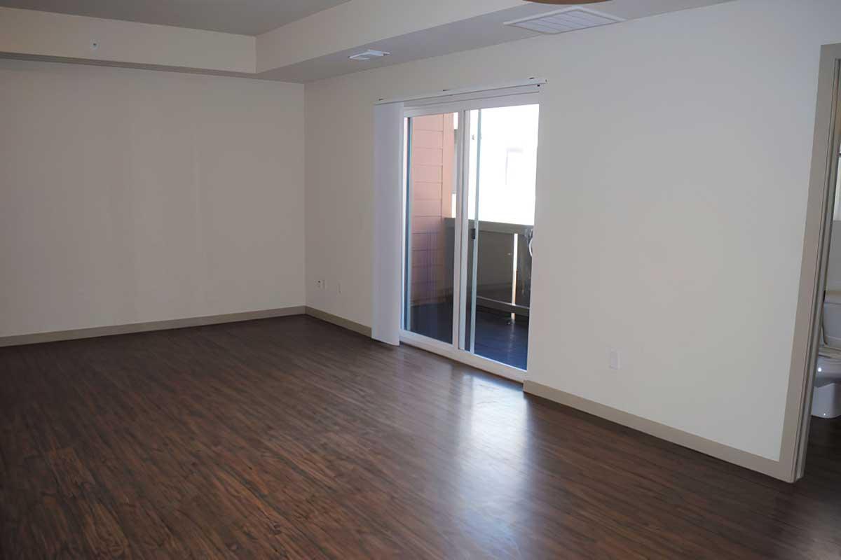 Spacious empty room with light-colored walls and hardwood flooring.