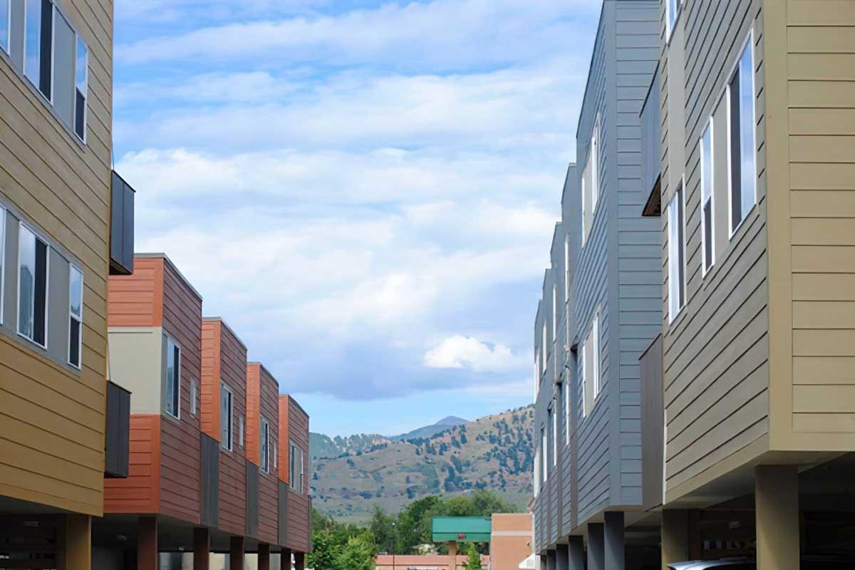 A view between two rows of modern multi-story buildings with a mix of brown and gray siding.