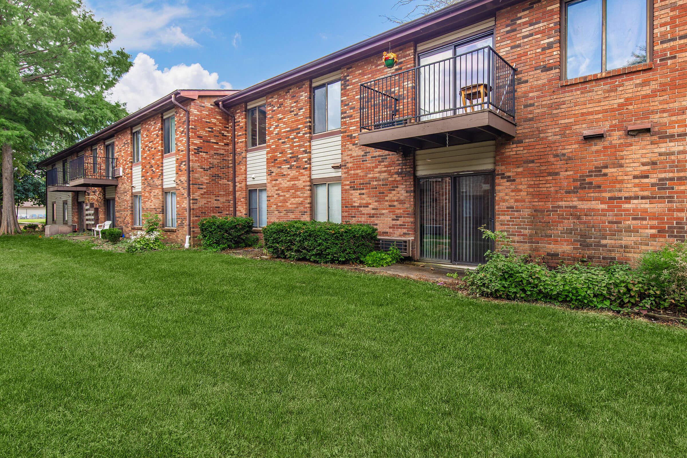 a large brick building with grass in front of a house