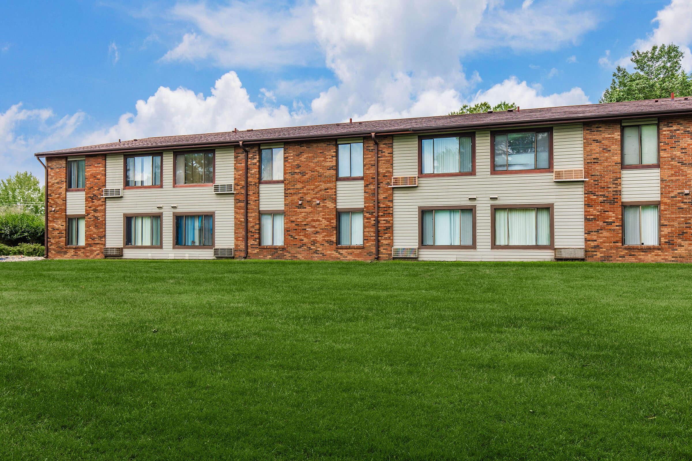 a large brick building with green grass in front of a house