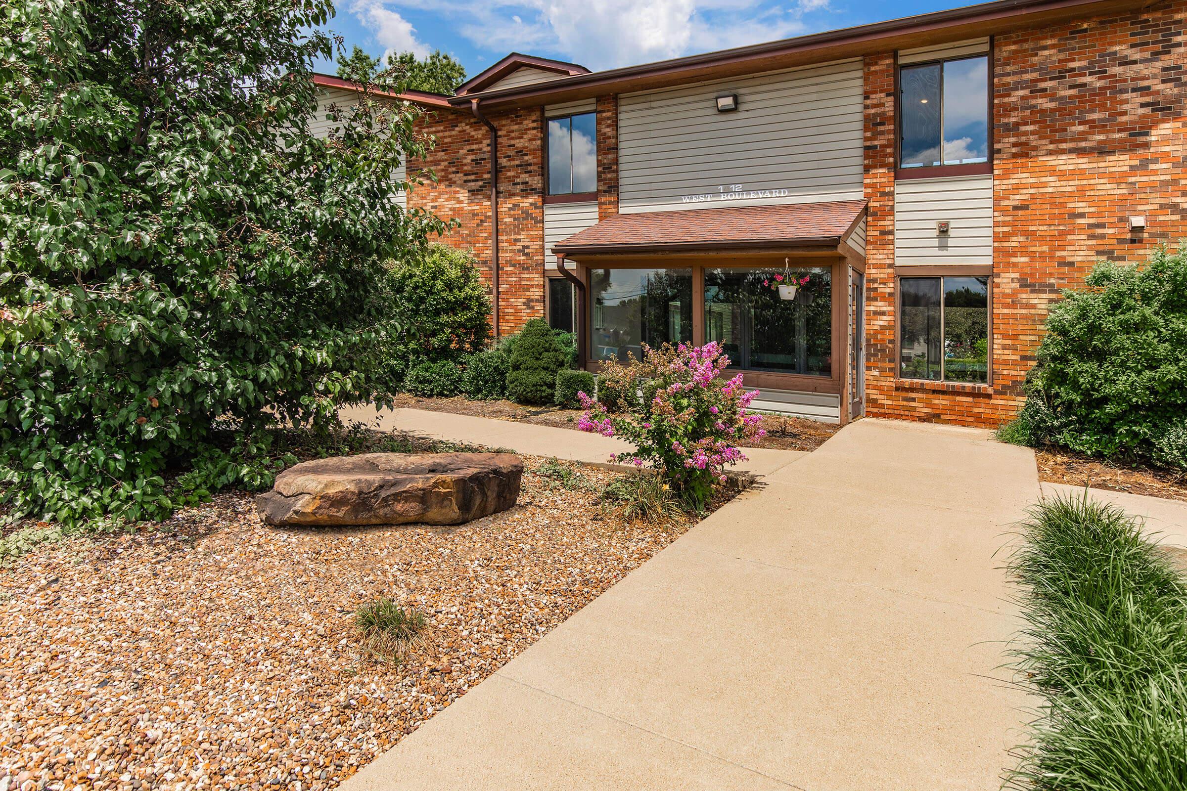 a house with bushes in front of a brick building