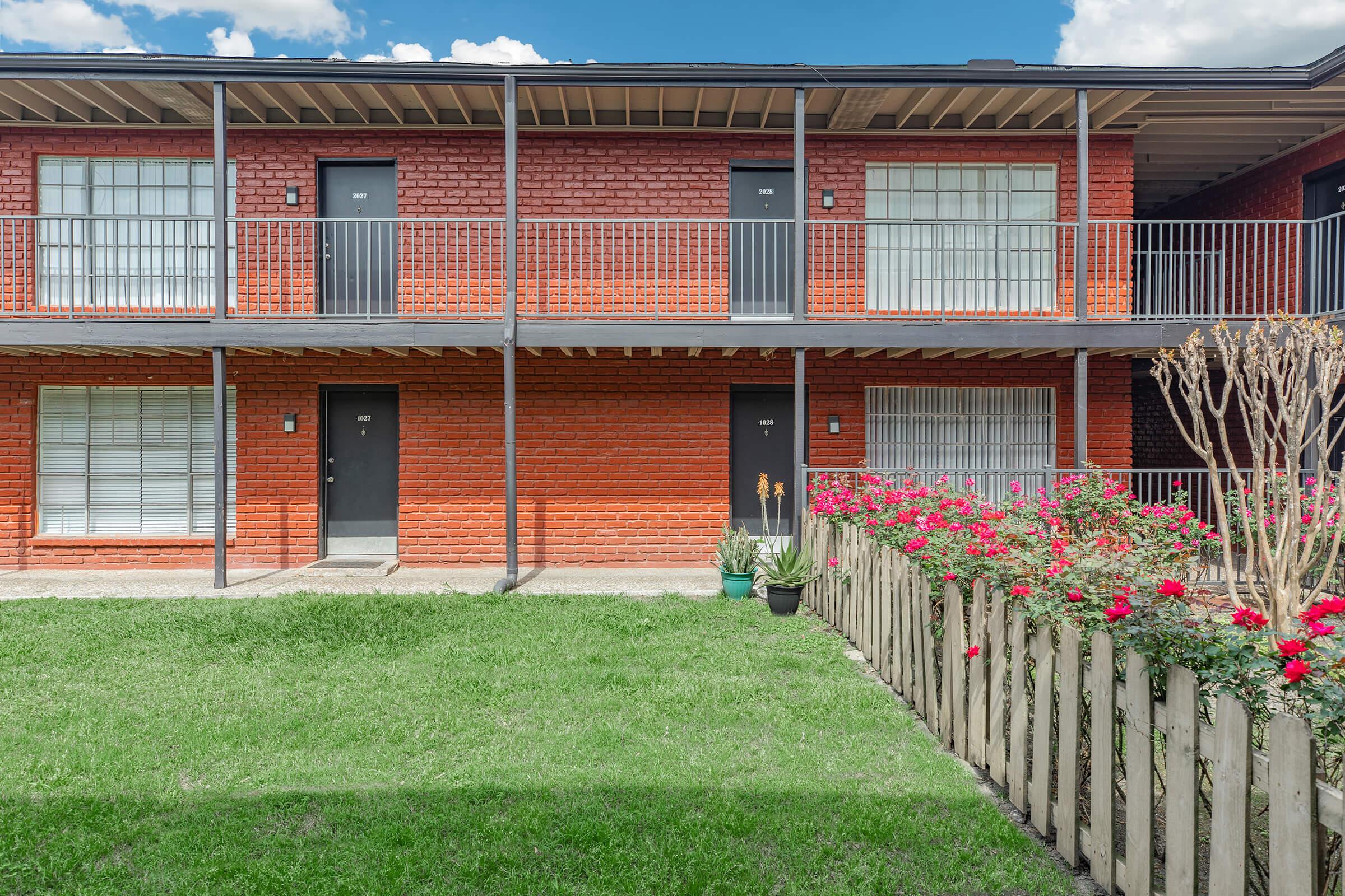 a house with a lawn in front of a brick building