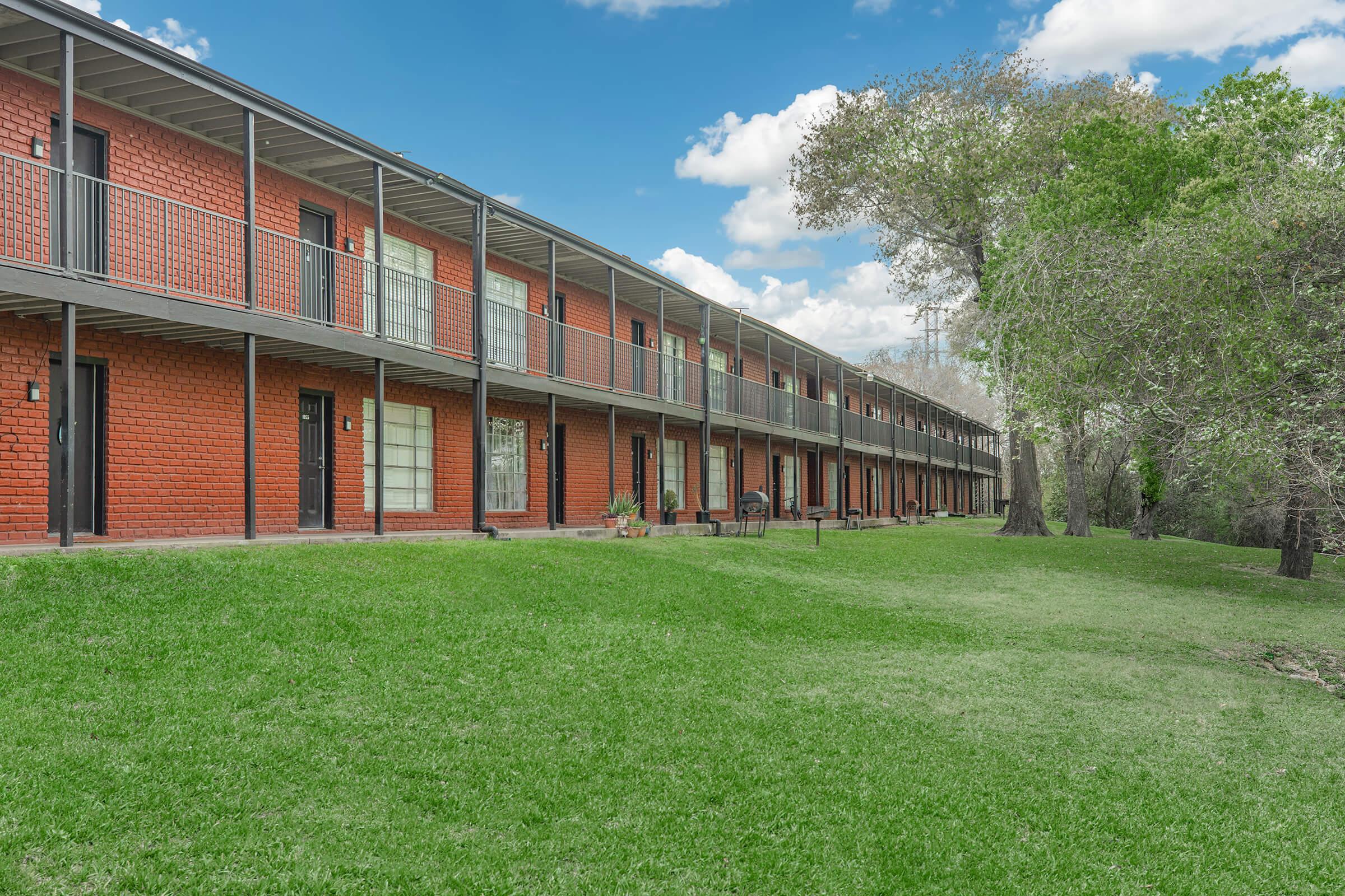 a large brick building with a grassy field