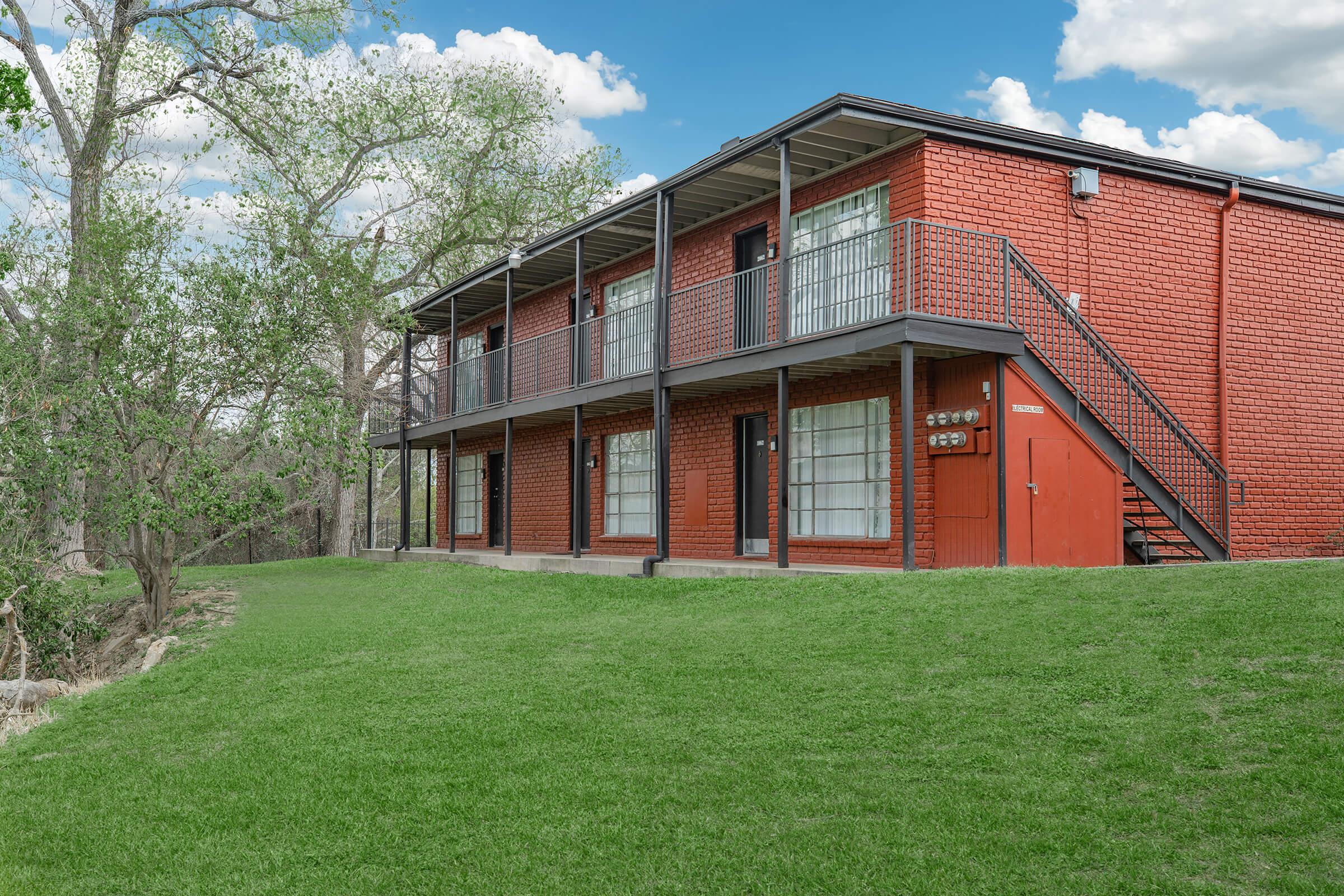 a large brick building with grass in front of a house