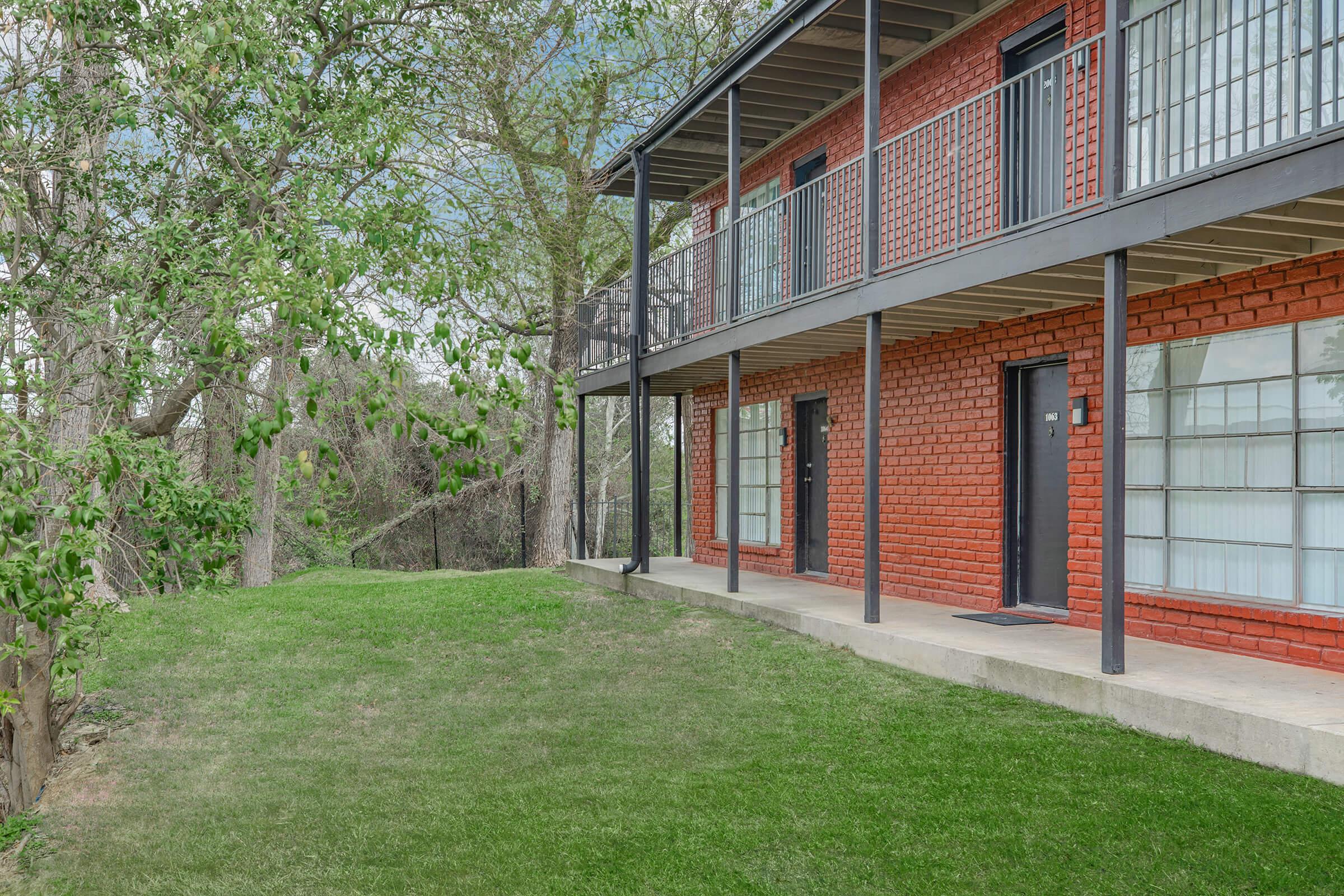 a large brick building with grass and trees