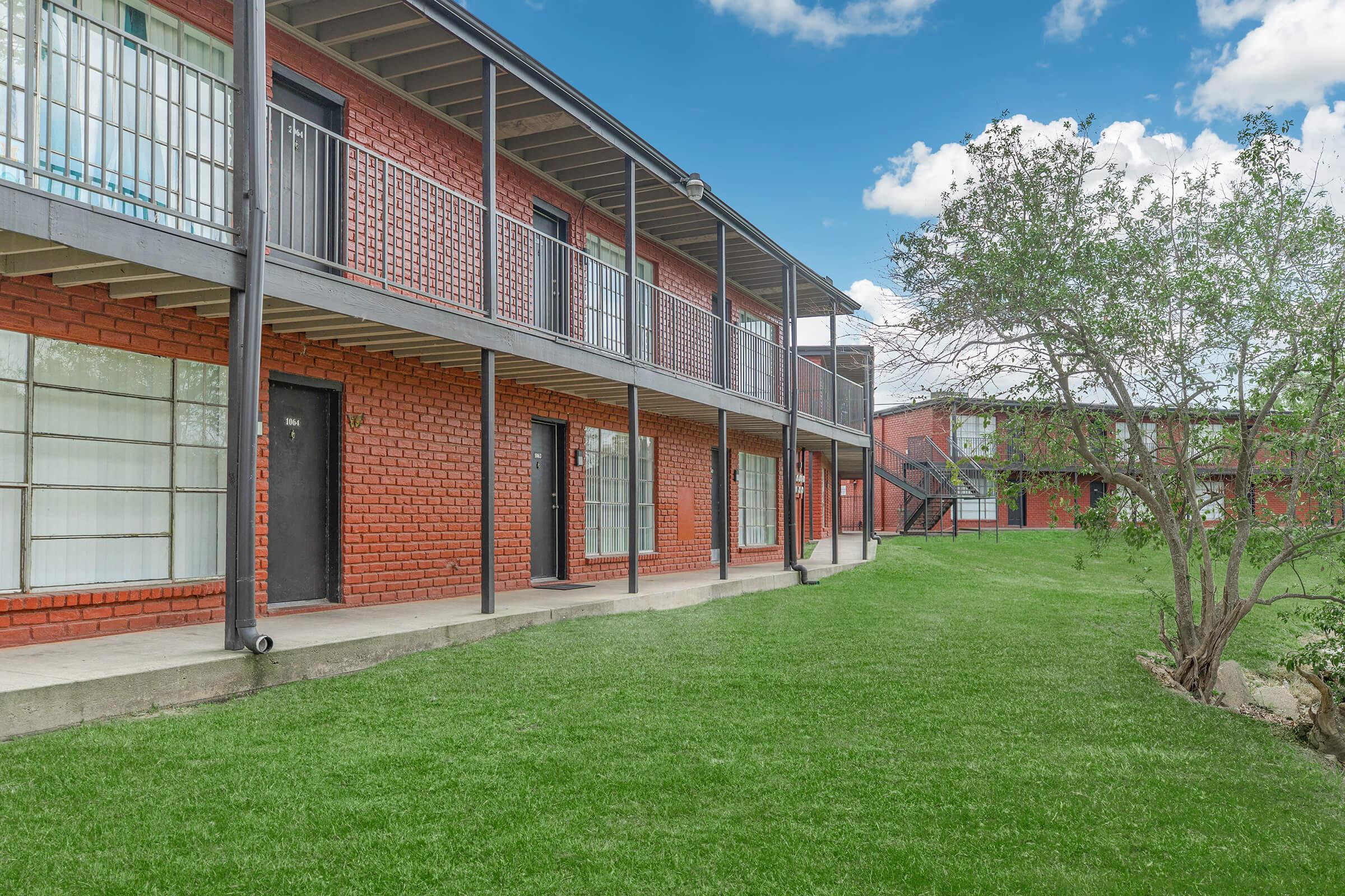 a large brick building with grass and trees