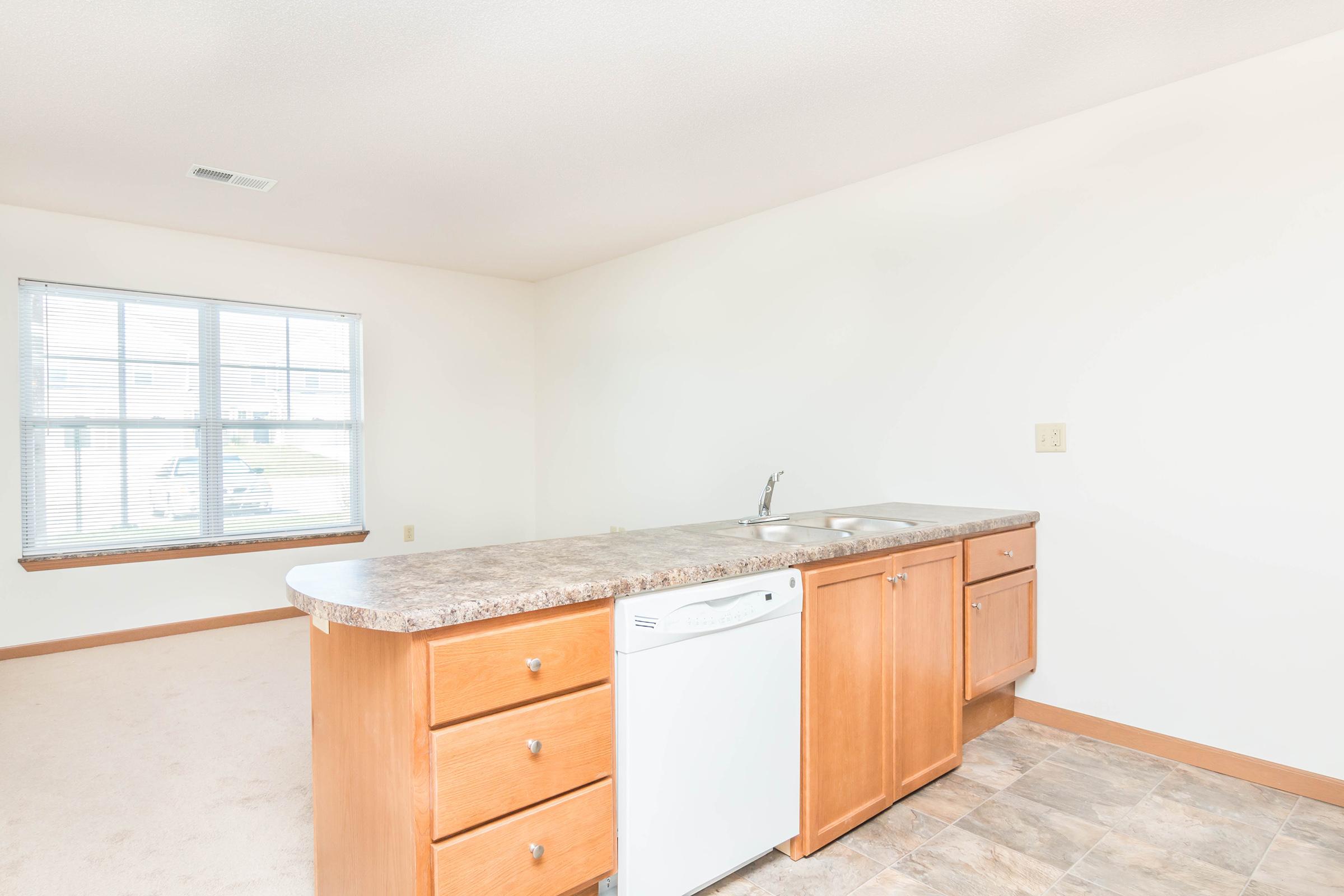 a kitchen with wooden cabinets and a large window