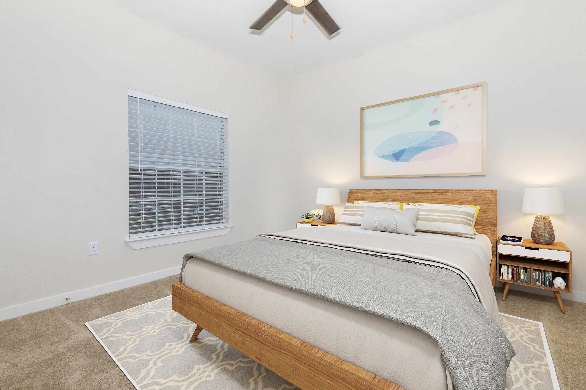 A cozy bedroom featuring a wooden bed with gray and yellow bedding, two bedside lamps, and a minimalist wall art piece. There's a window with white blinds, light-colored walls, and a soft area rug complementing the space. A small bookshelf is visible beside the bed.