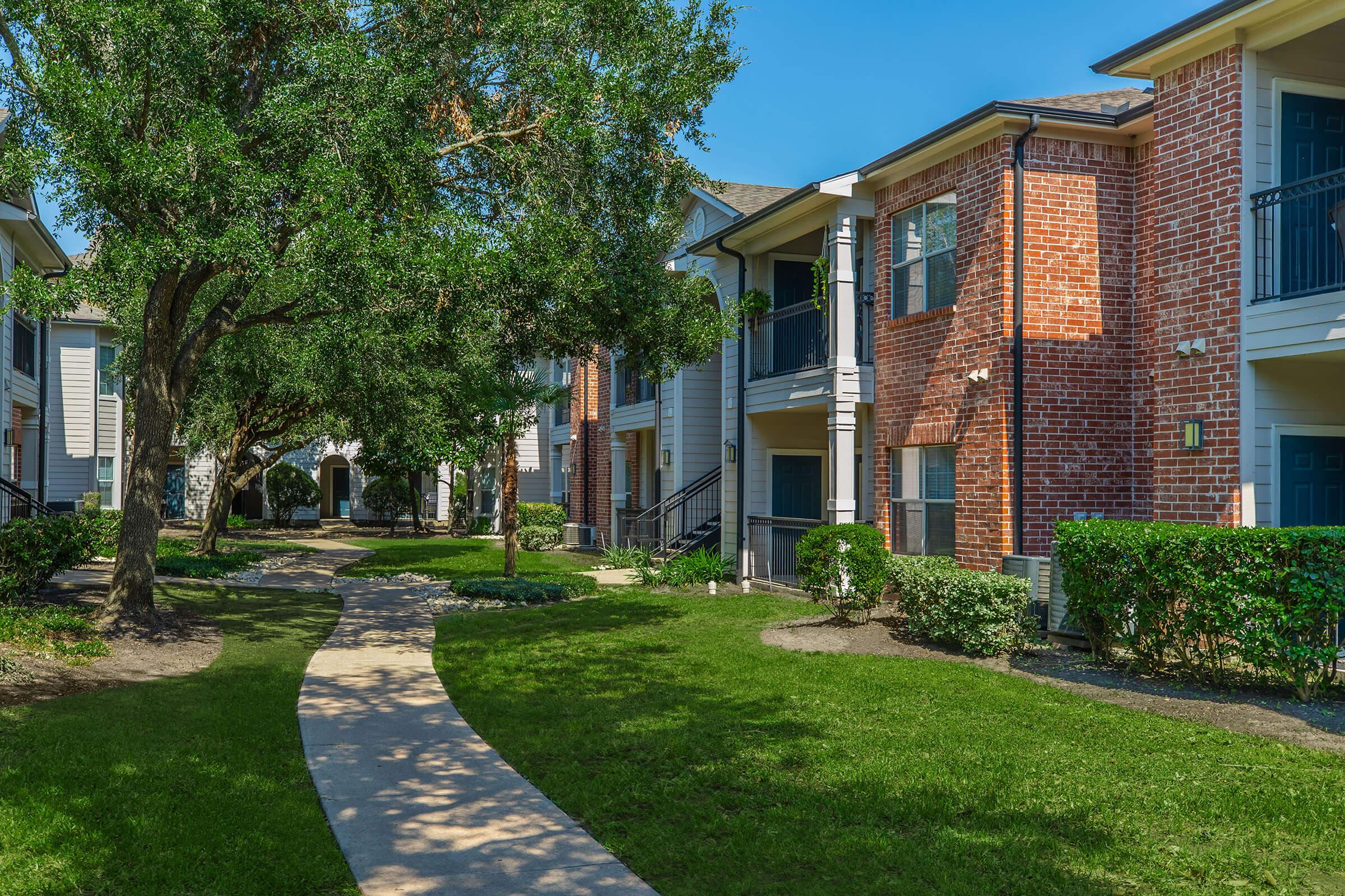 a house with a lawn in front of a brick building