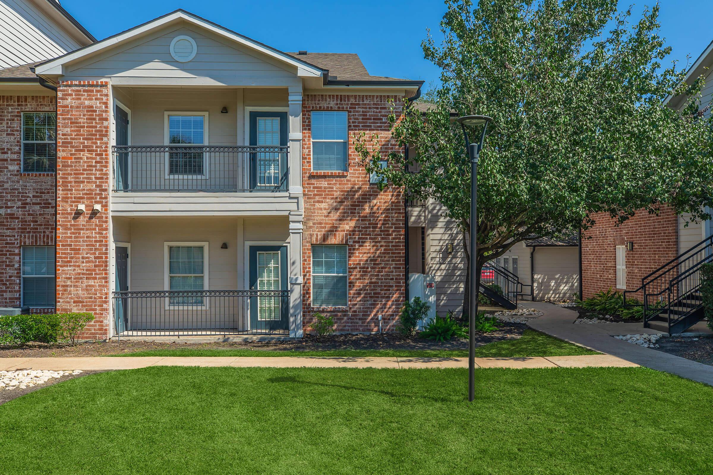 a house with a lawn in front of a brick building