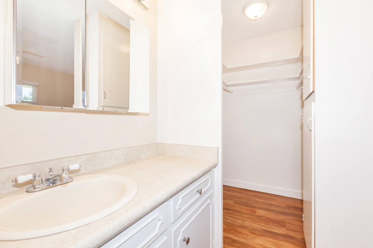 a white sink sitting under a mirror