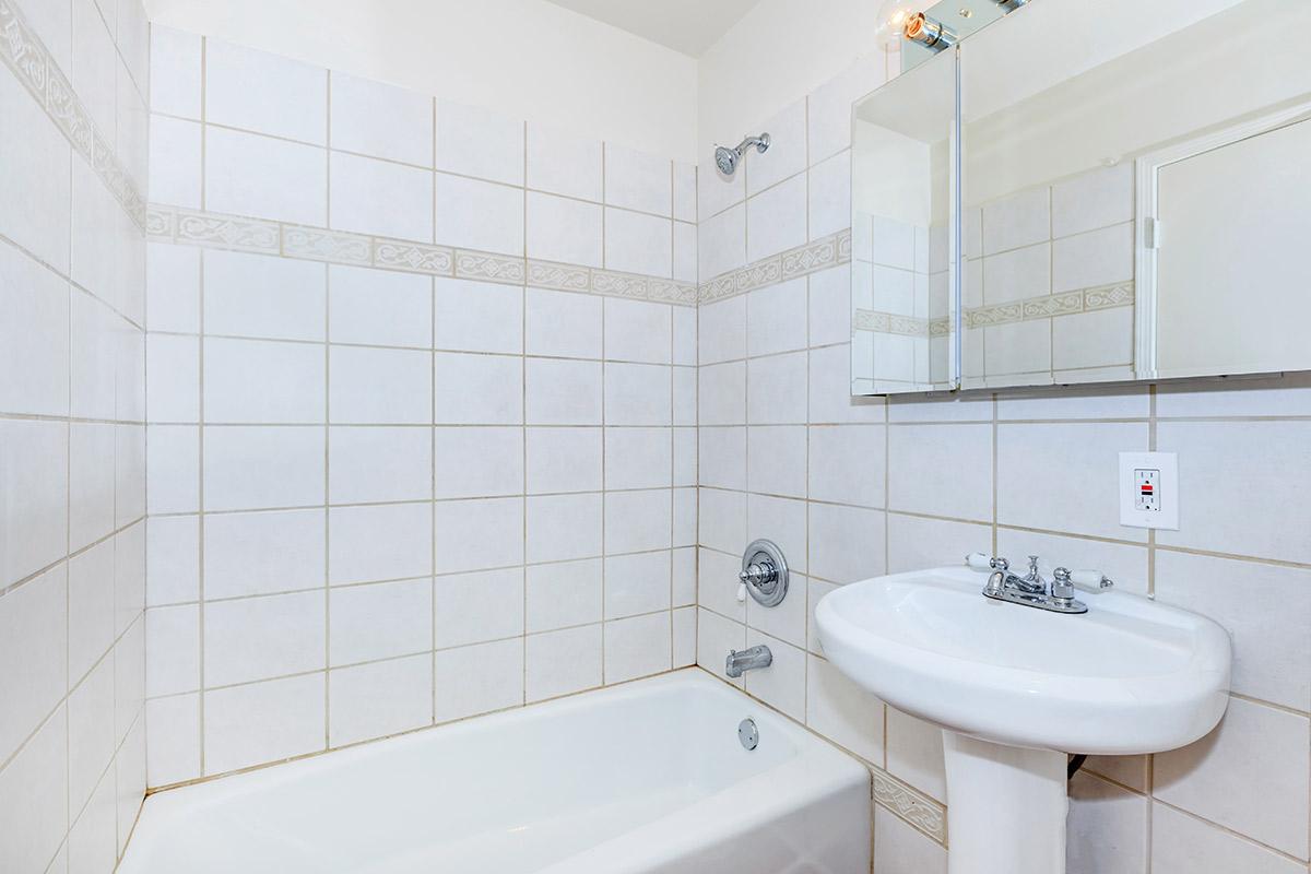 a white sink sitting next to a tiled wall