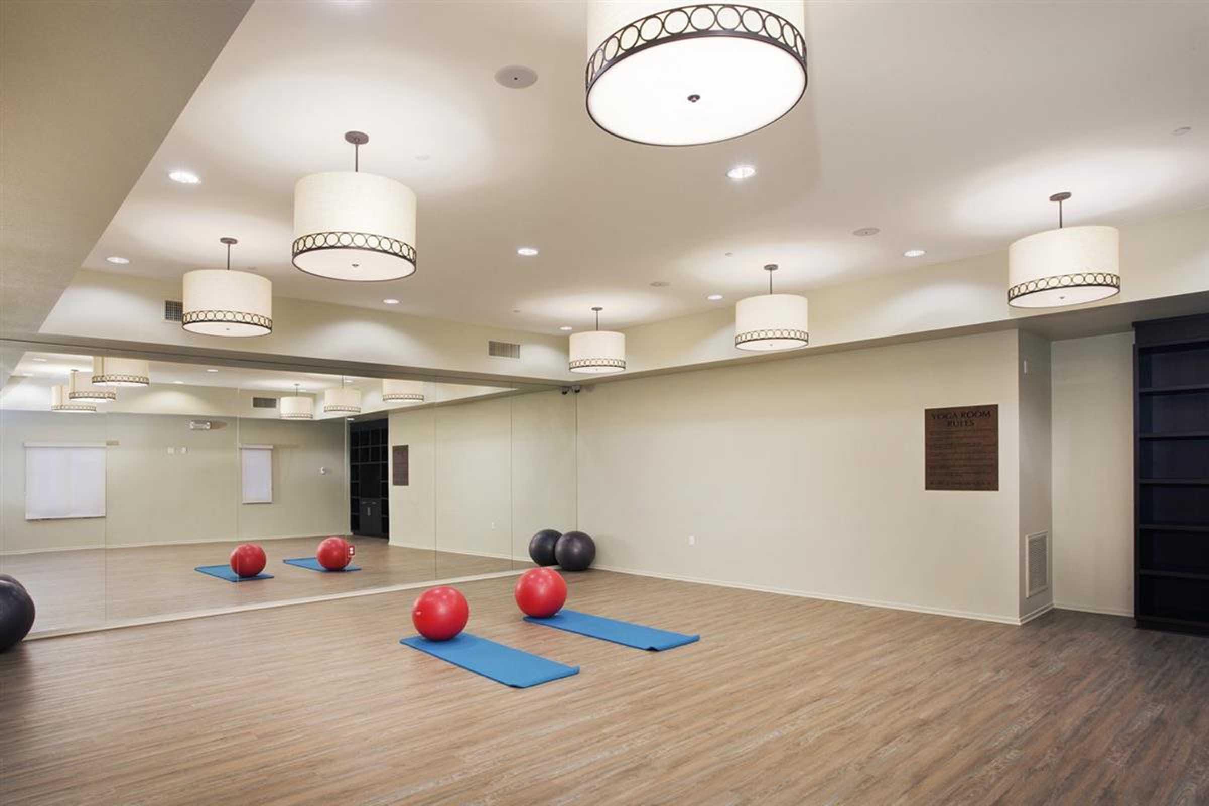 a large room with a mirrored wall and yoga mats