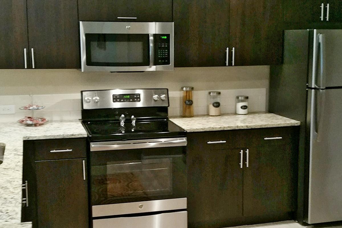 a stove top oven sitting inside of a kitchen with stainless steel appliances