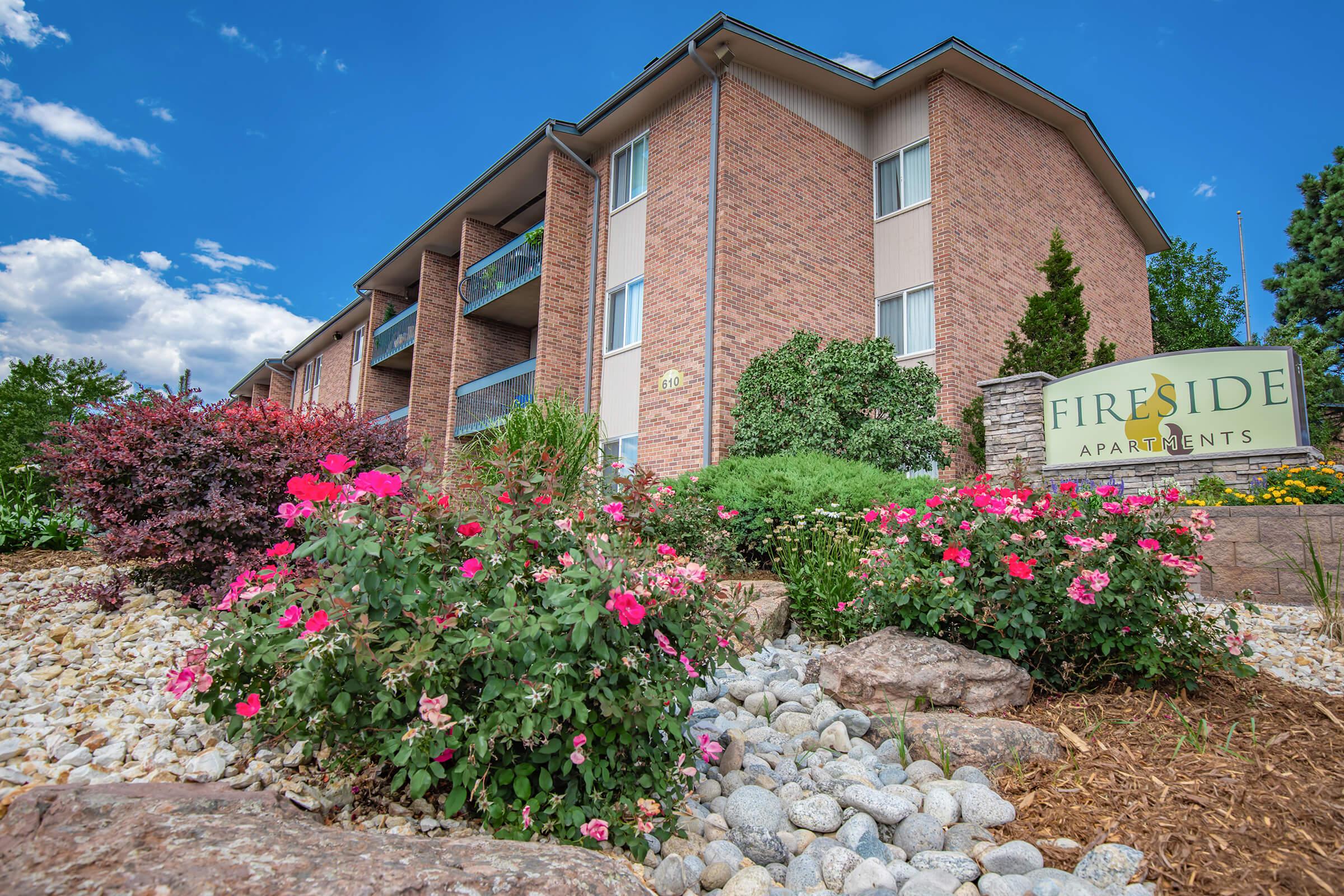 a close up of a flower garden in front of a brick building