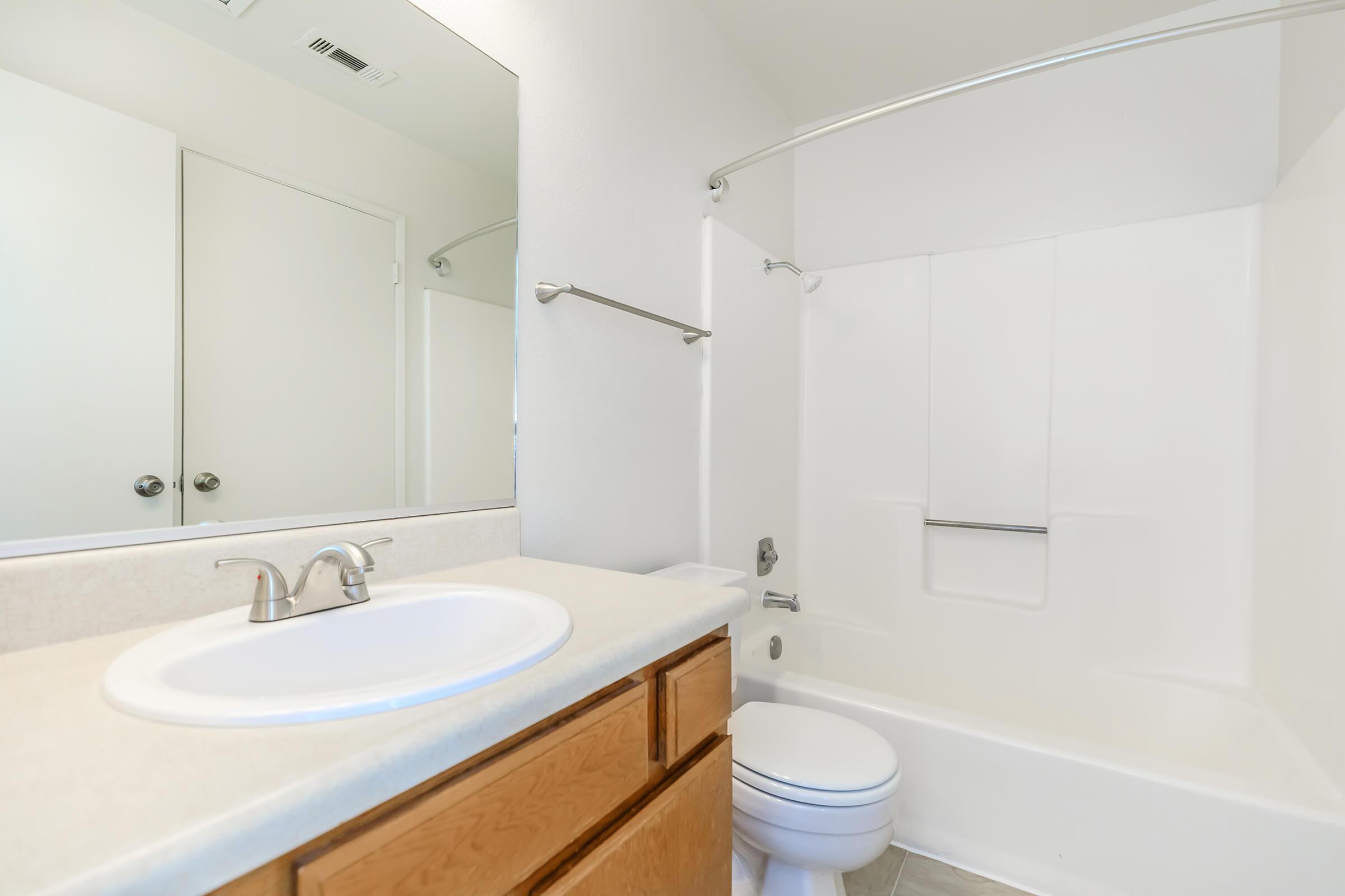 a white sink sitting under a mirror