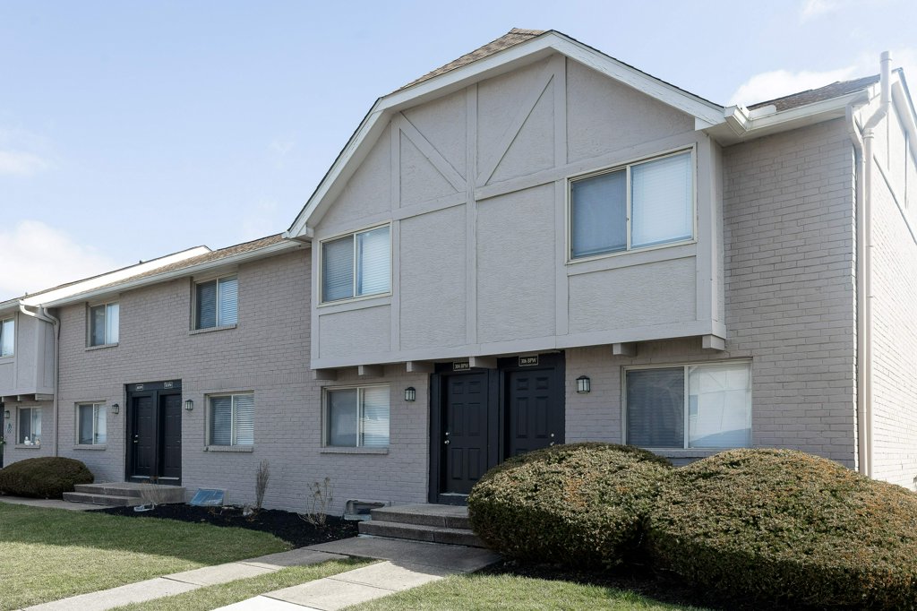 a large brick building with grass in front of a house