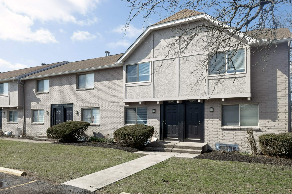 a large brick building with grass in front of a house