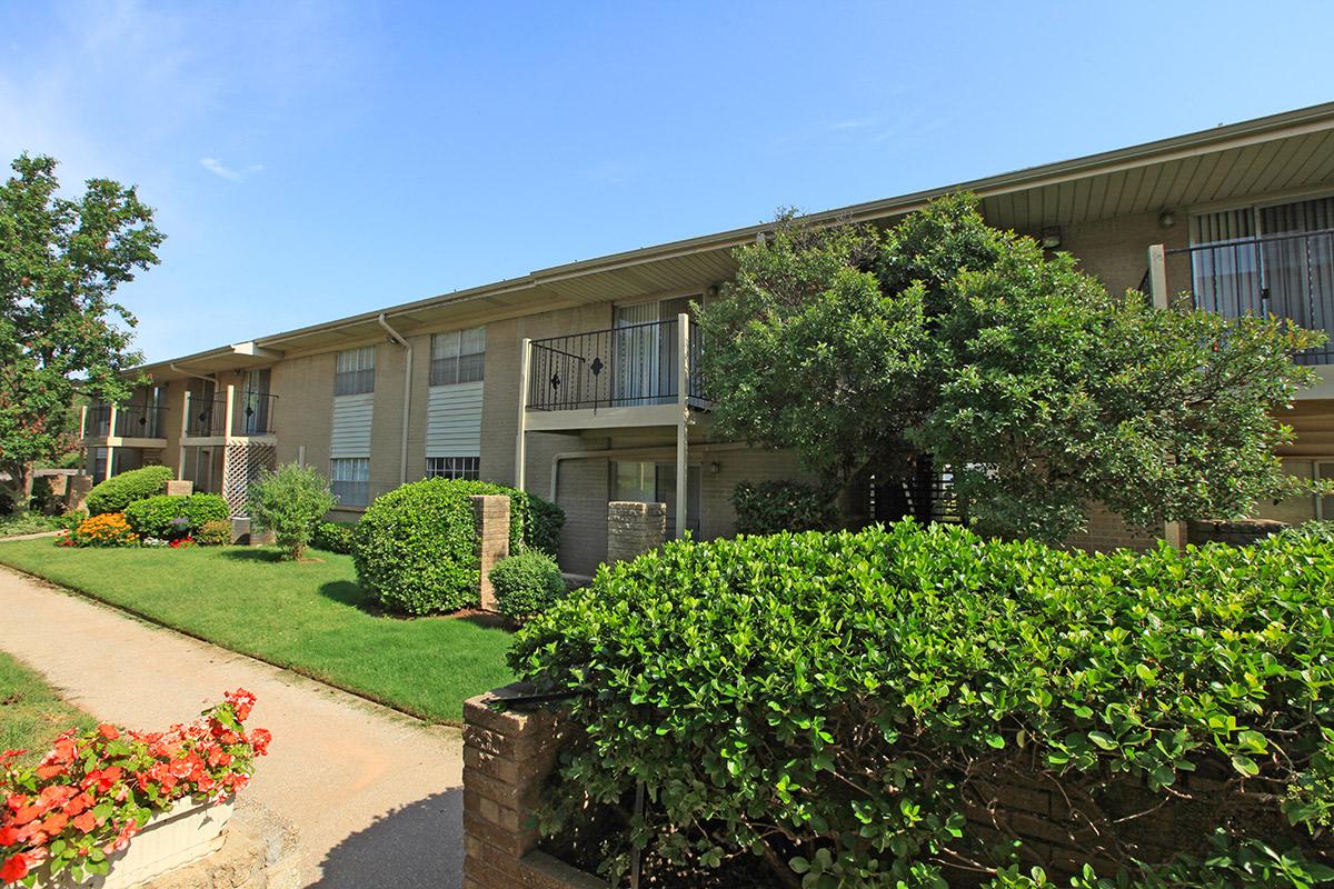 a house with bushes in front of a brick building