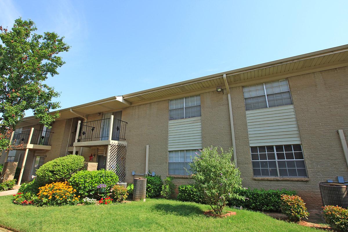 a house with bushes in front of a brick building