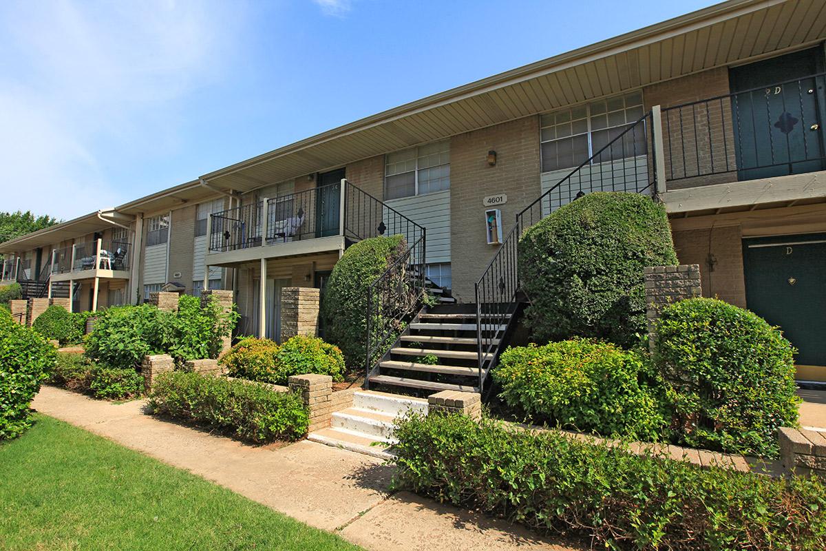 a house with bushes in front of a brick building