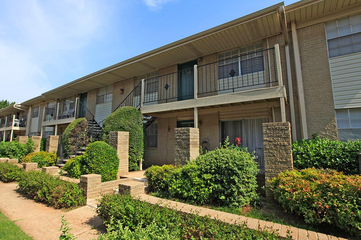 a house with bushes in front of a brick building