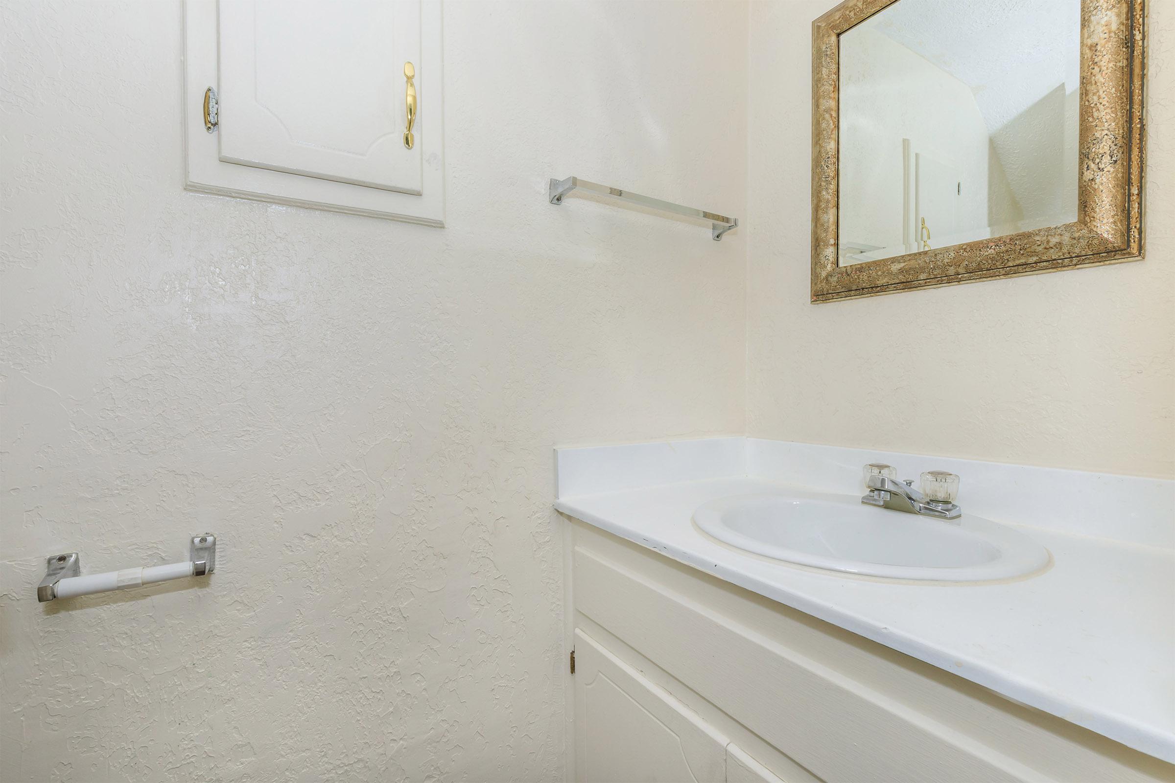 a white sink sitting underneath a mirror in a room