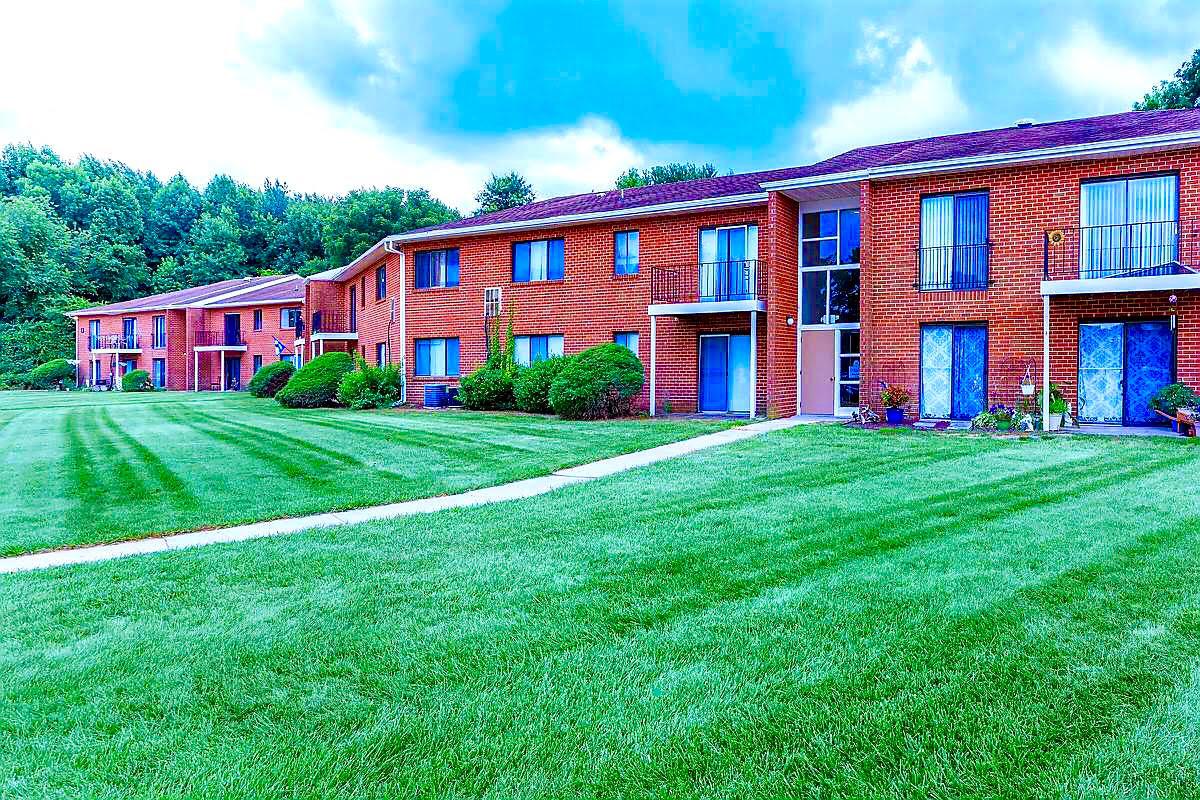 a large brick building with green grass in front of a house